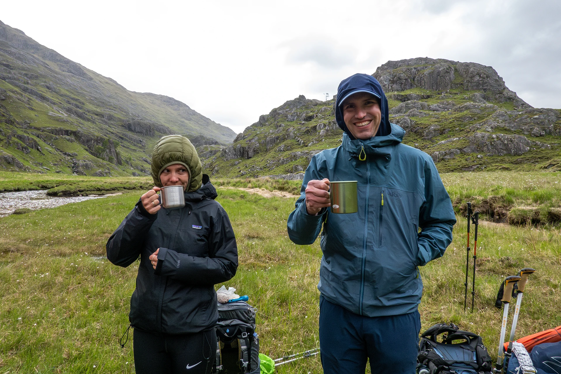 Twee mensen die warme drank vasthouden in een nat berggebied