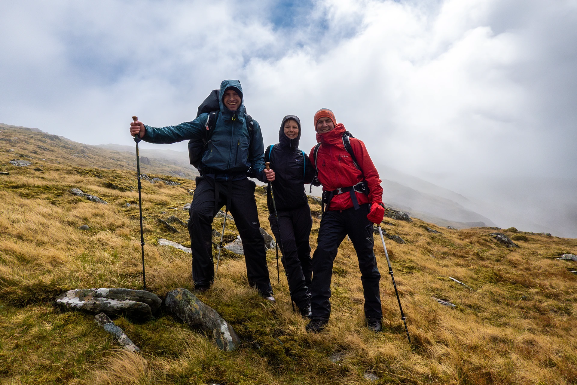 Twee wandelaars die op een hoogtepunt poseren met trekkingstokken