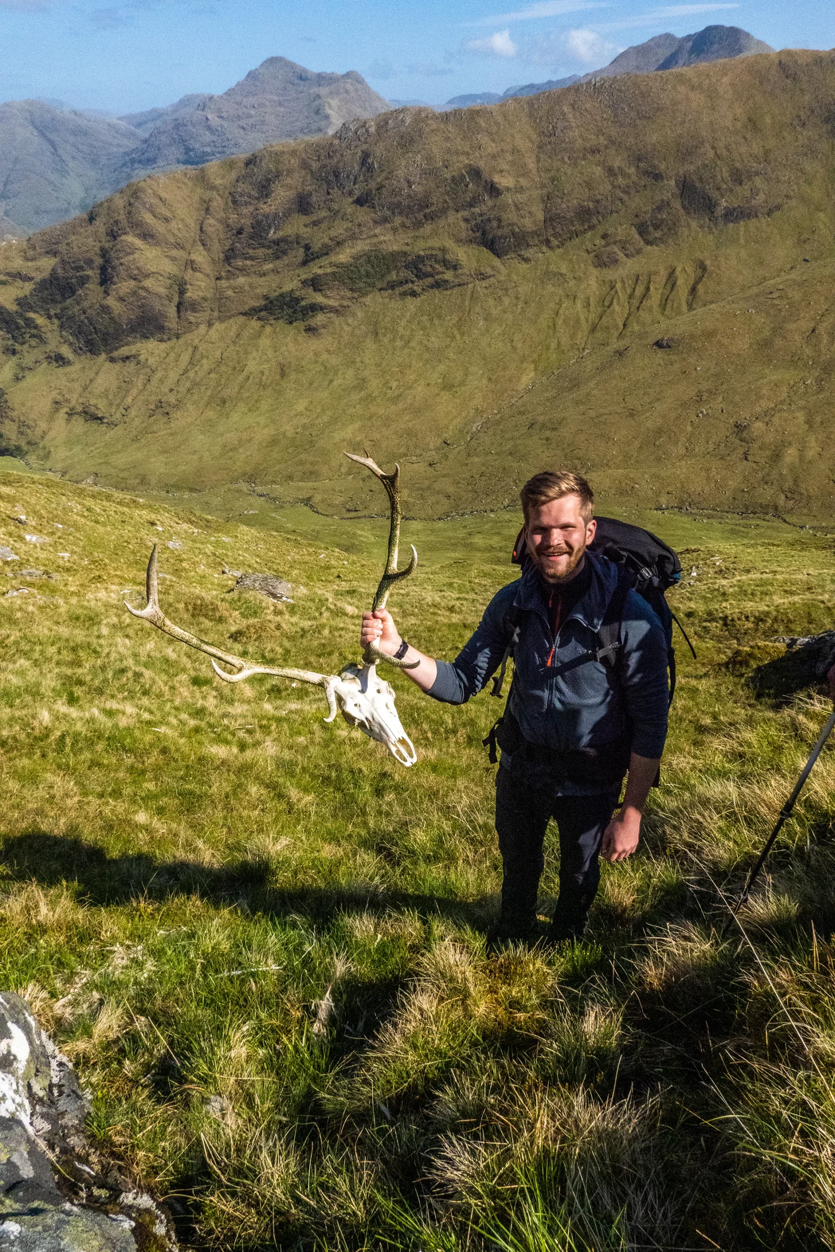 Wandelaar die lacht met een wandelstok in een nat groen berggebied