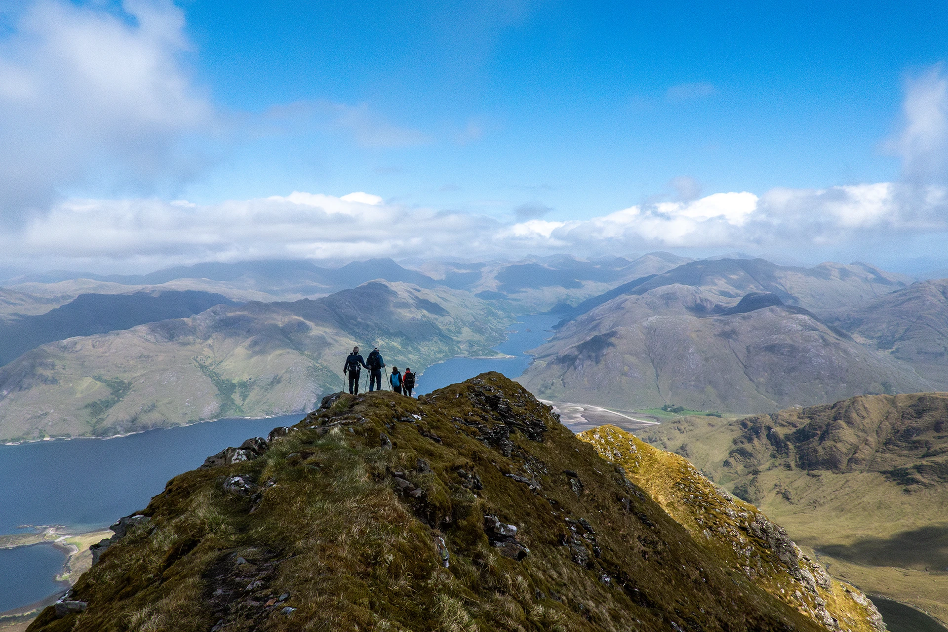 Drie hikers op een smalle graat met valleien aan beide kanten