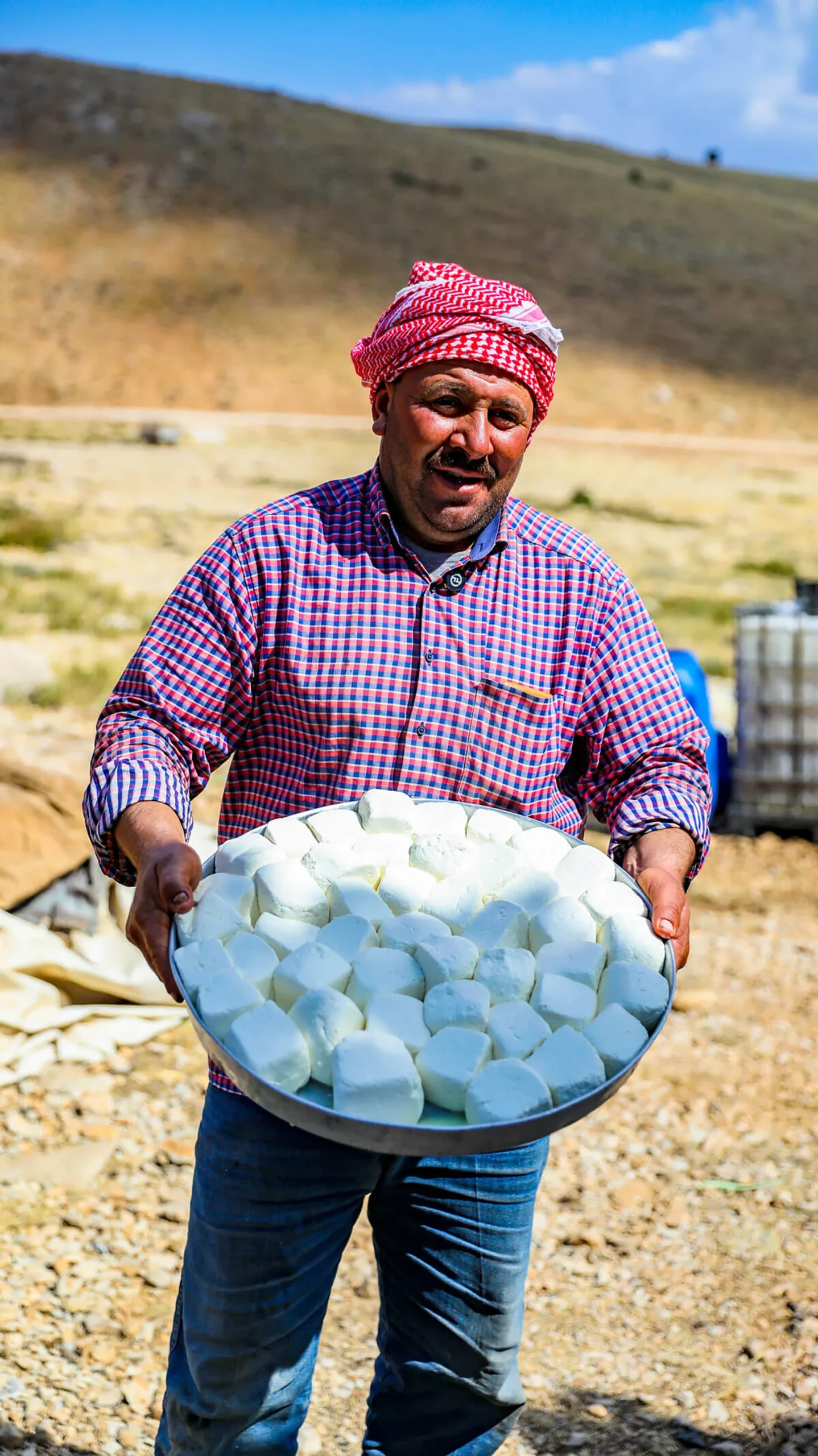 Man die een schaal vol witte kaas toont in een droge omgeving