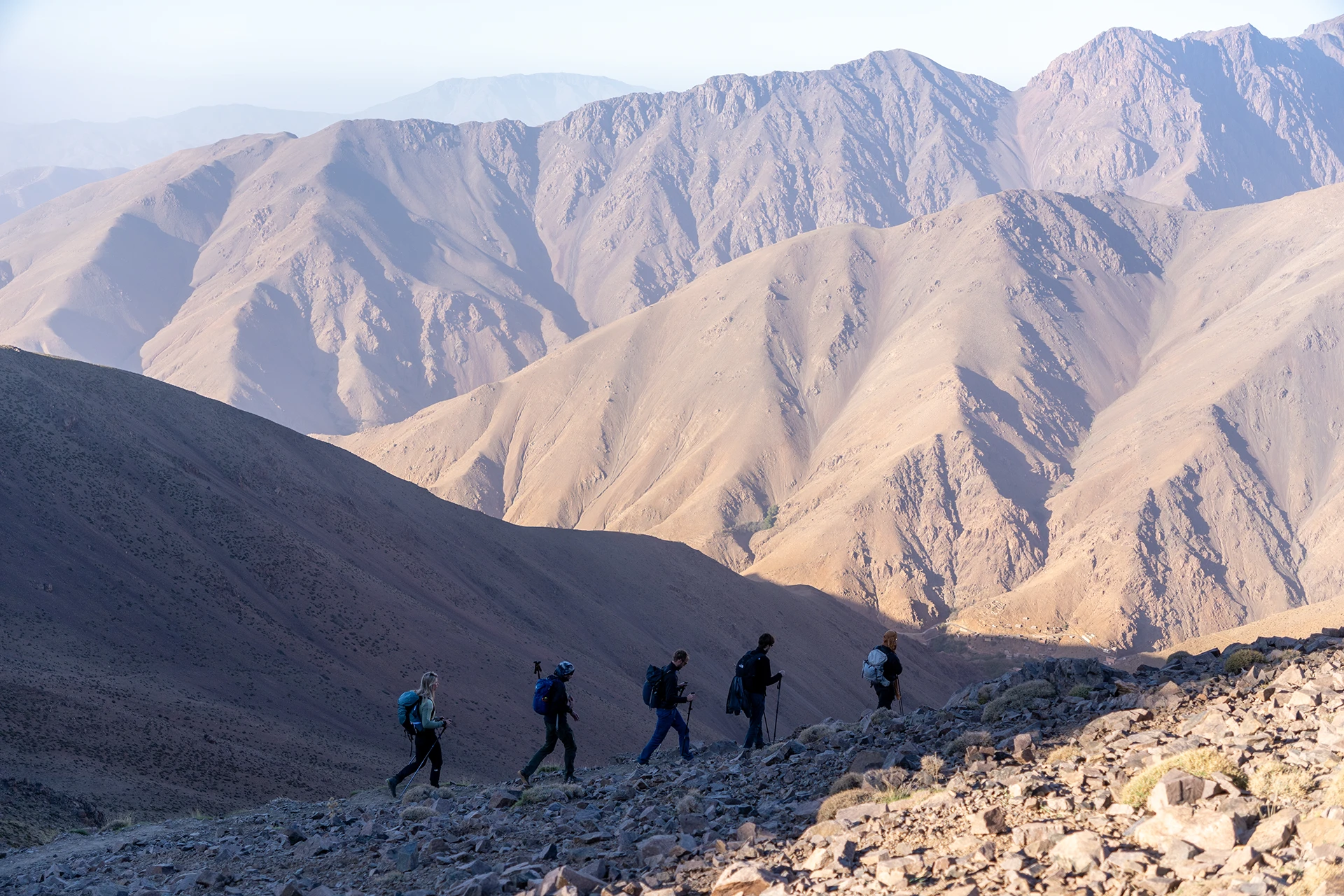 Wandelgroep die een steile zandkleurige bergpas oversteekt