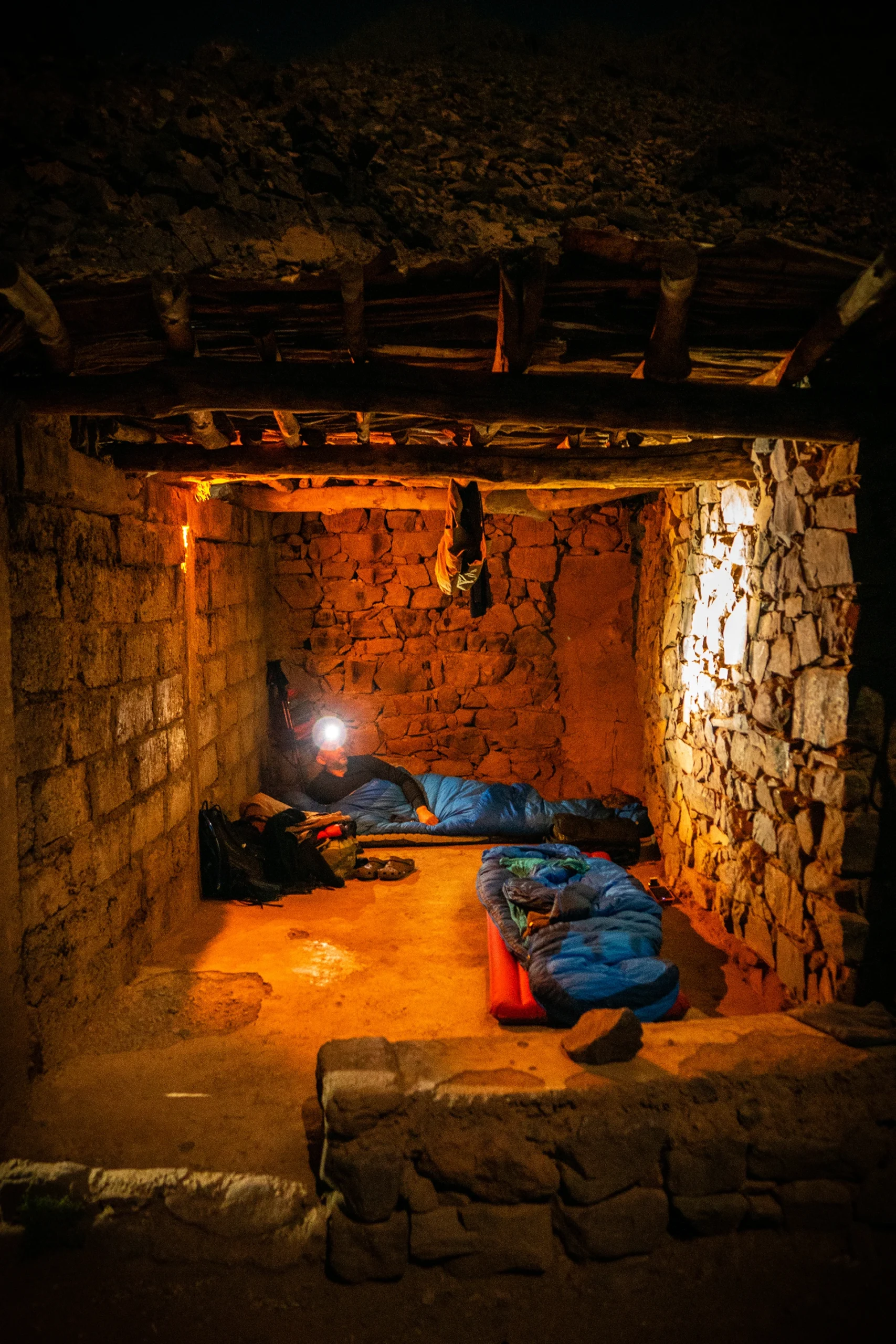Binnenruimte van een berghut met slaapzakken en warm licht