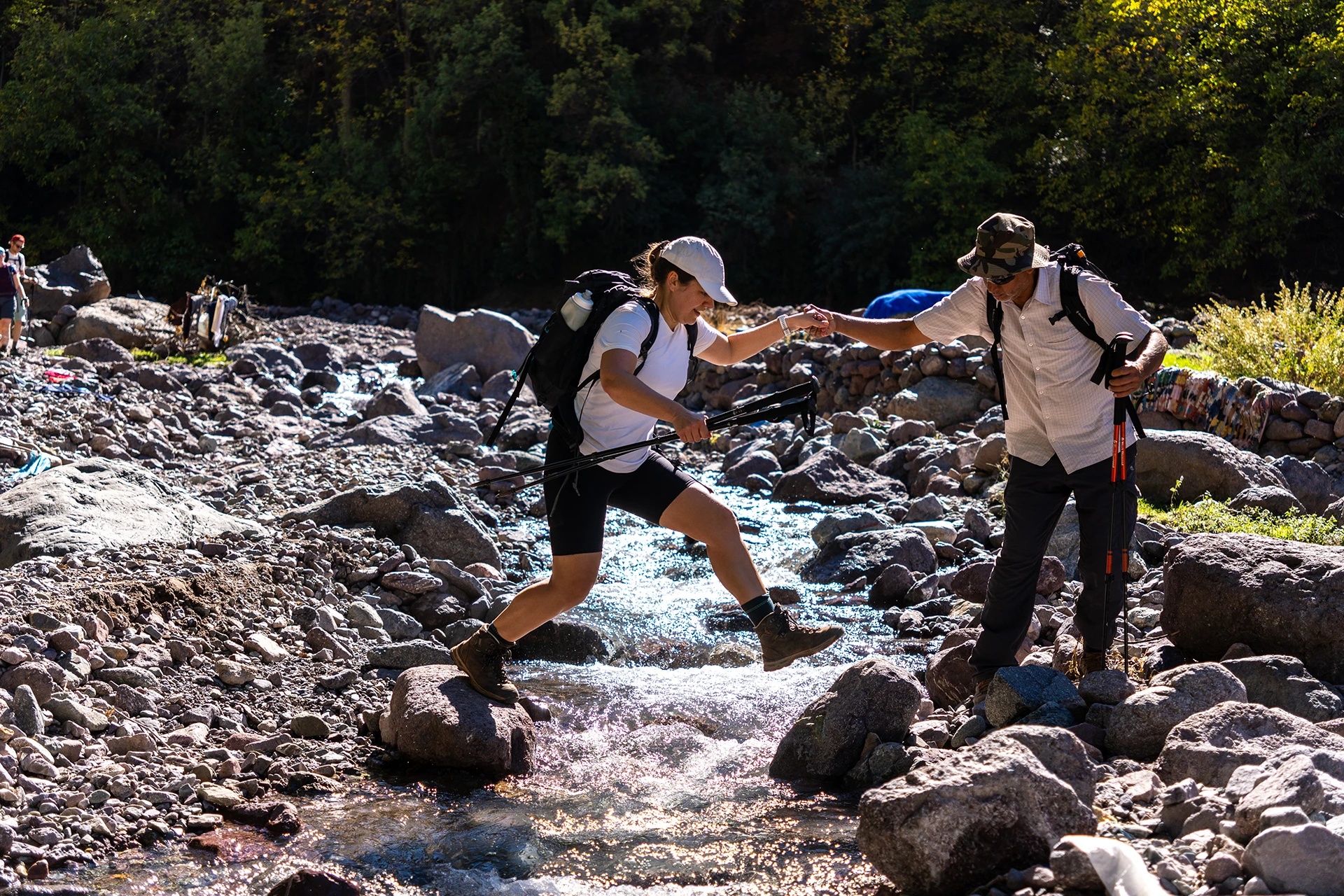 Twee hikers die elkaar helpen bij het oversteken van een rivier