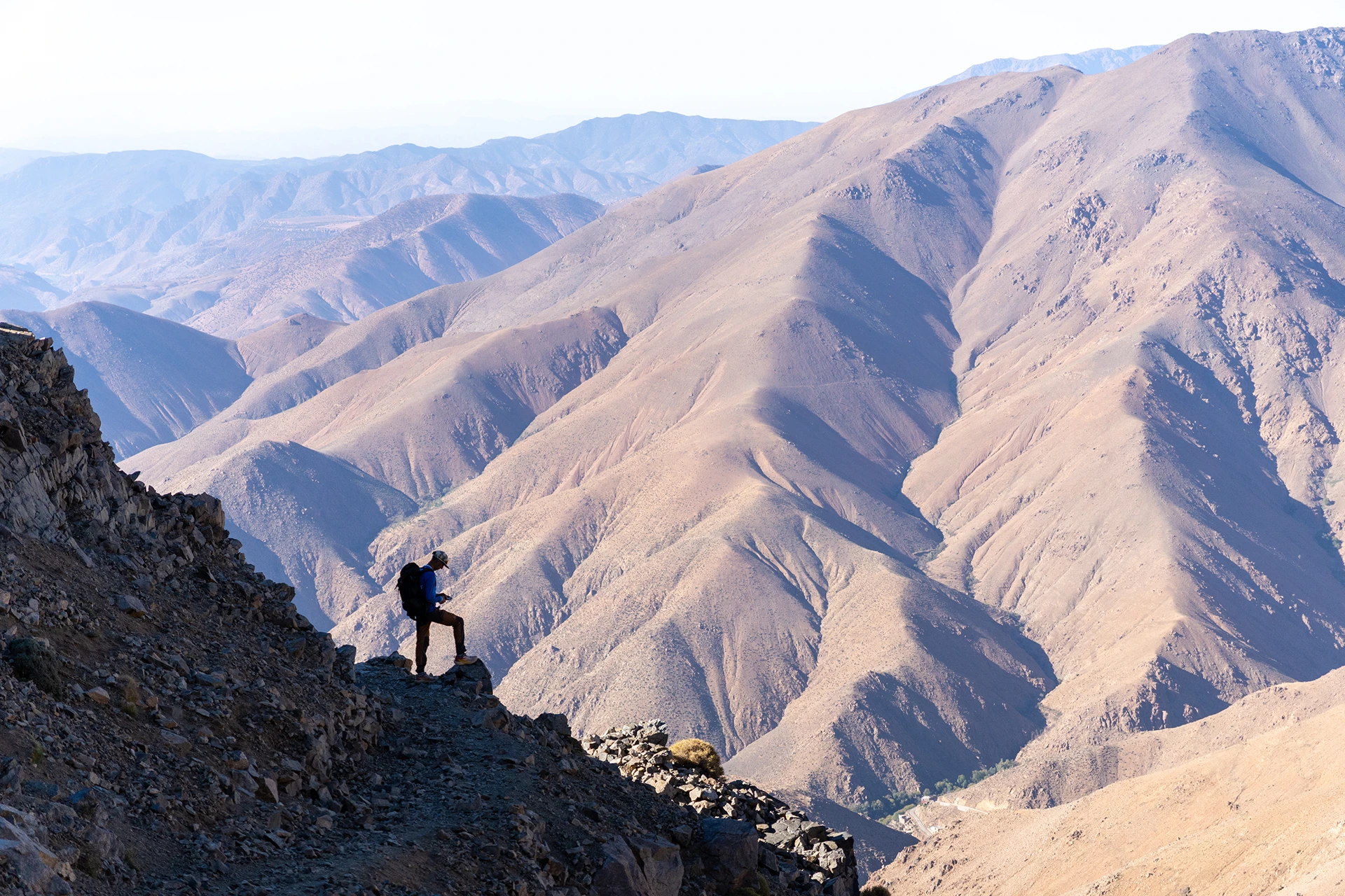 Hiker die langs een smalle bergkam loopt met diepe dalen om zich heen