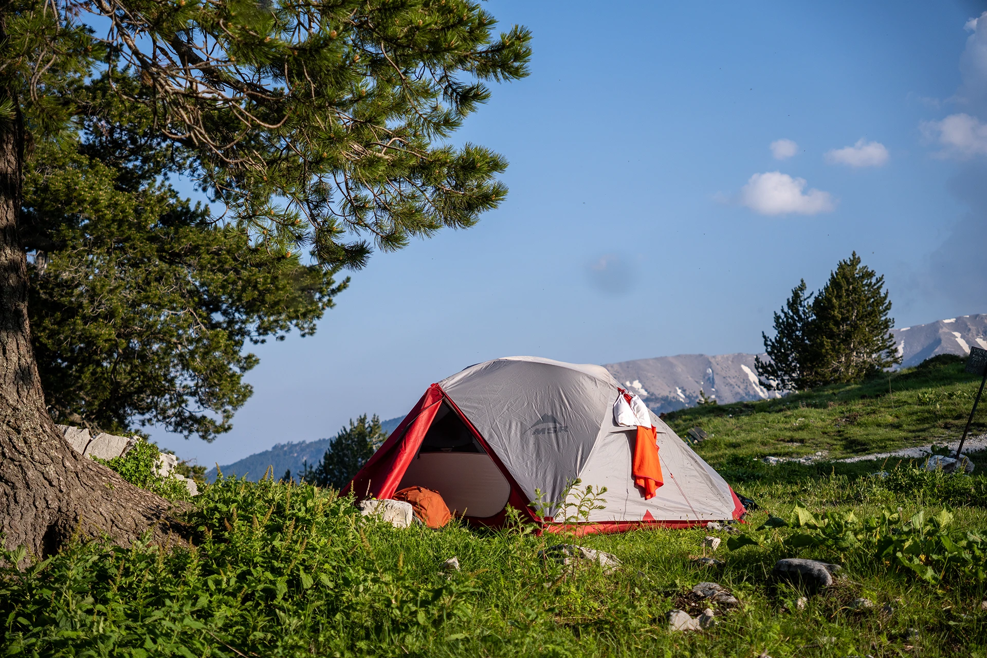 Tent in ochtendlicht op een grasrijke helling