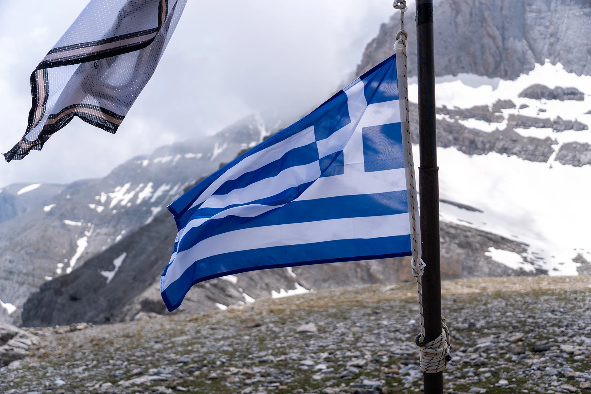 Griekse vlag die wappert met besneeuwde bergtoppen op de achtergrond