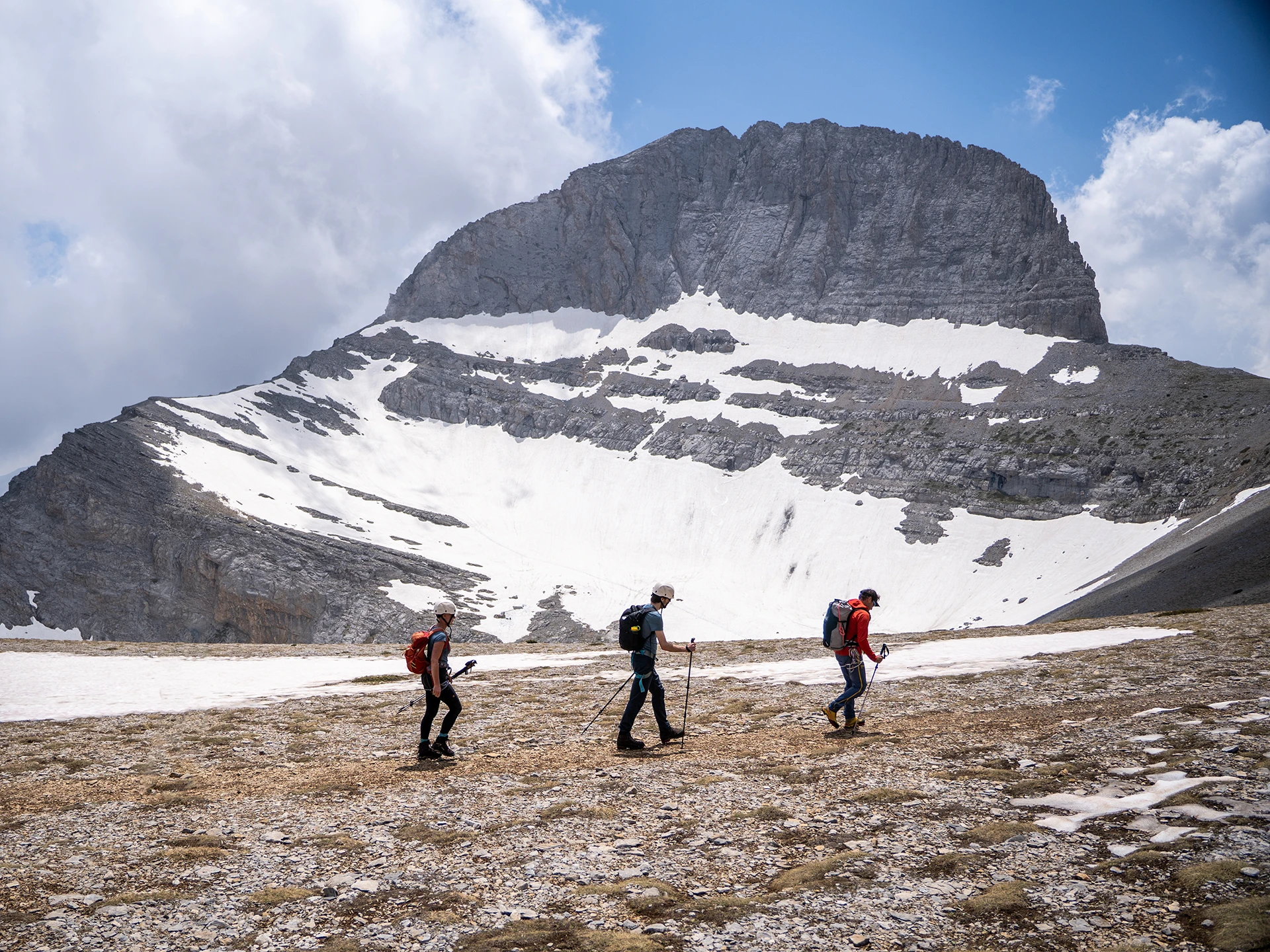 Wandelaars die over een sneeuwveld onder een hoge bergkam trekken