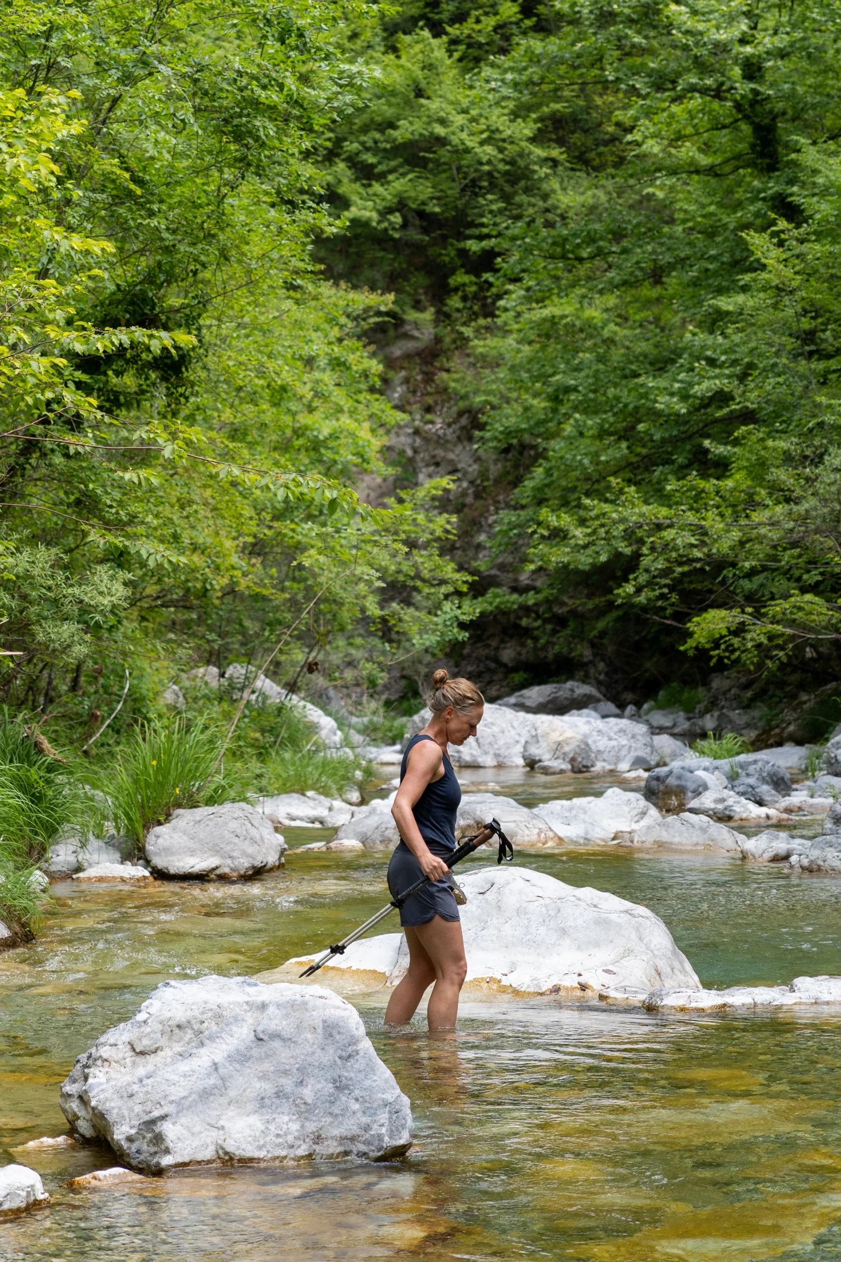 Persoon die in helder water staat tussen groene rotsen
