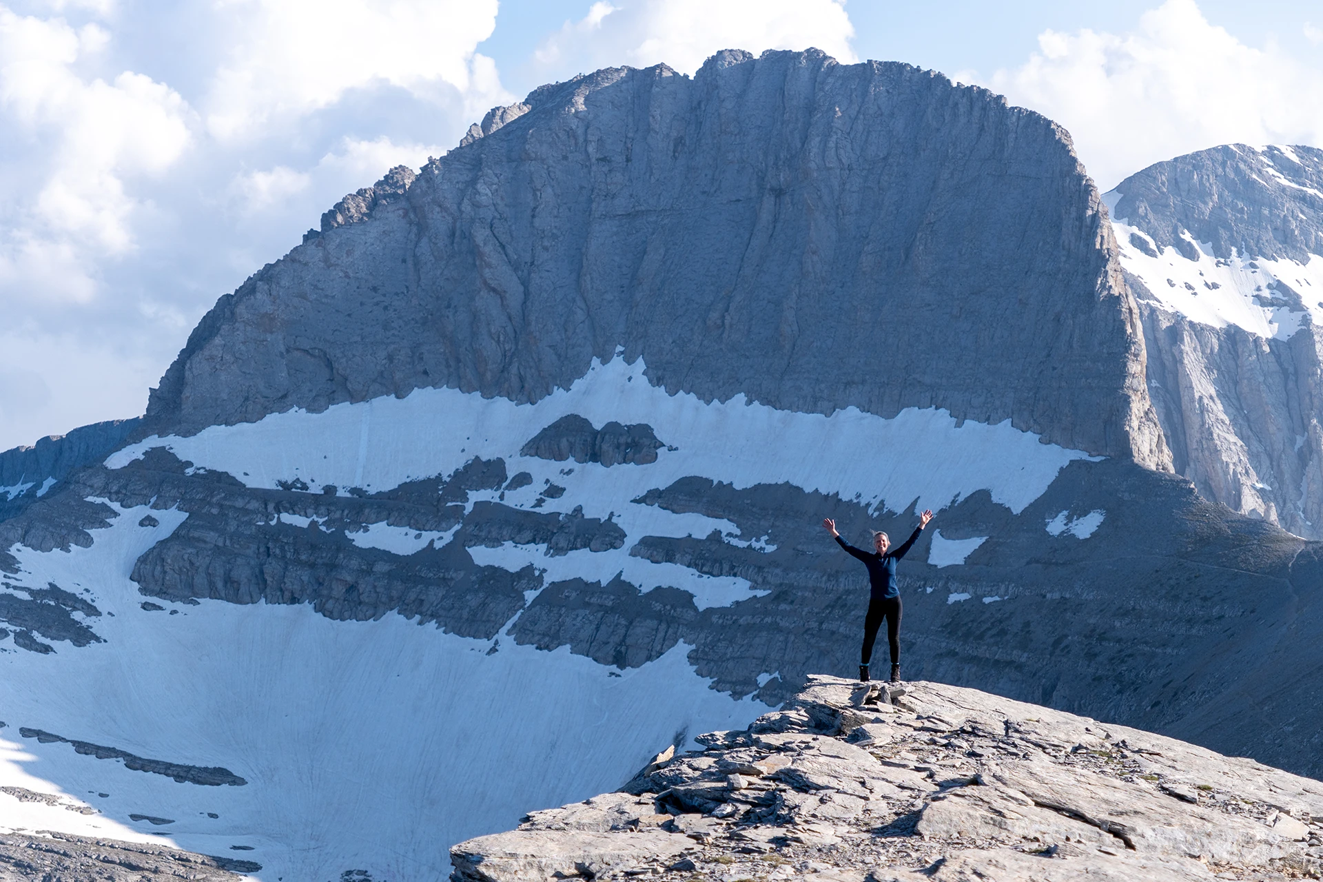 Hiker die poseert op een besneeuwde bergplaat bij een diepe kloof