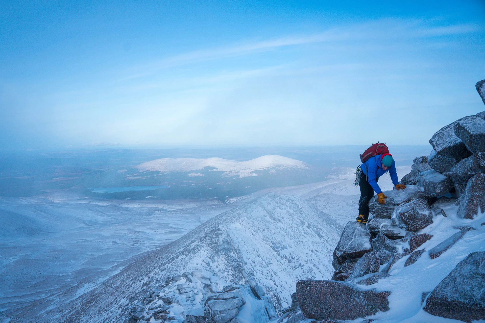 Hiker die een besneeuwde rotswand beklimt bij zonsopkomst