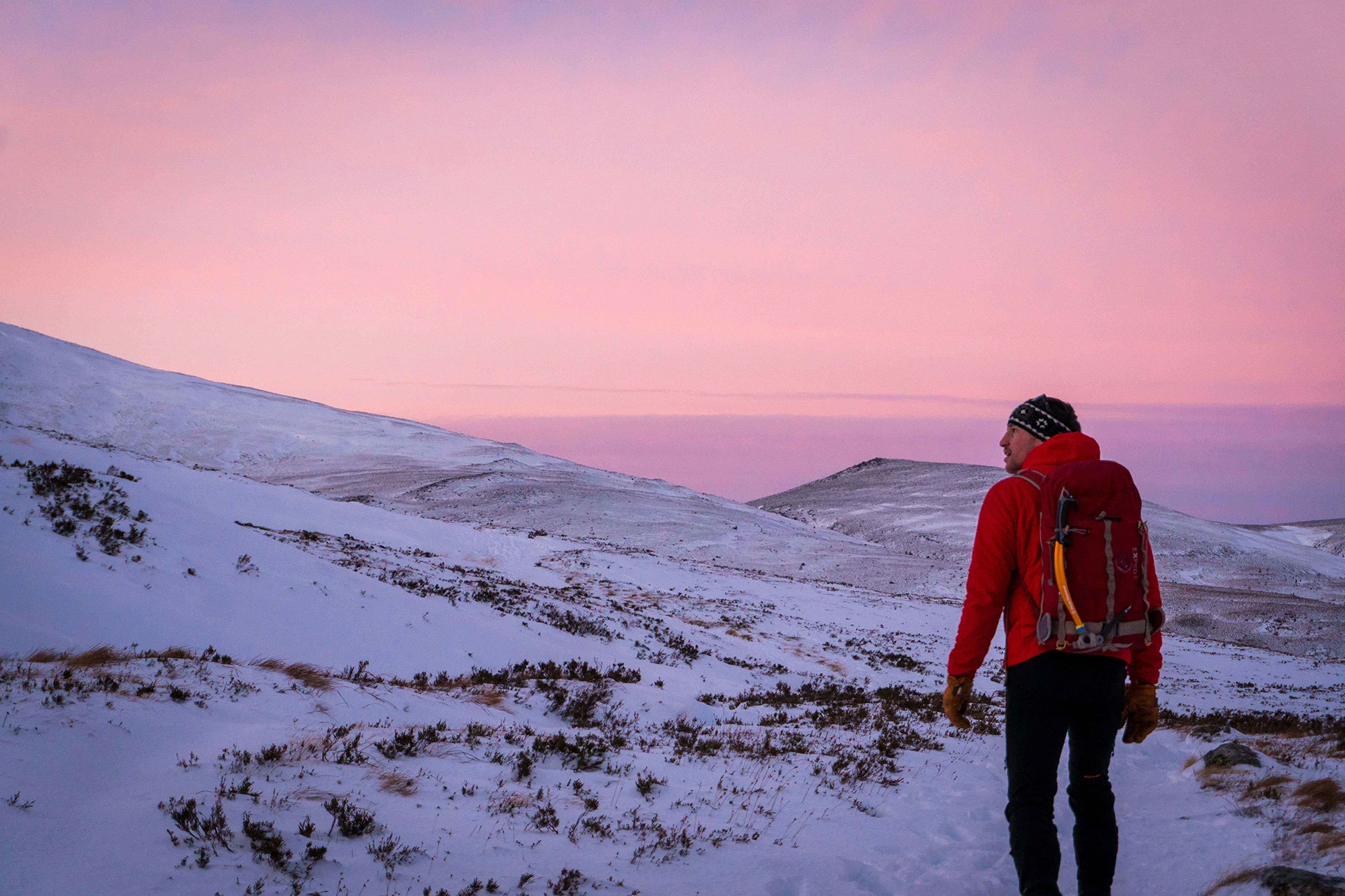 Hiker die over een roze gekleurde sneeuwhelling wandelt