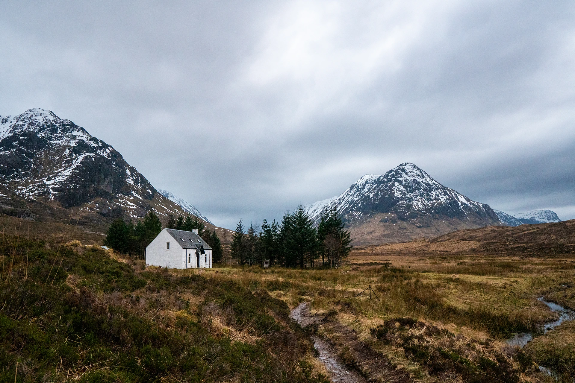 Wit kerkje tussen groene heuvels en besneeuwde toppen