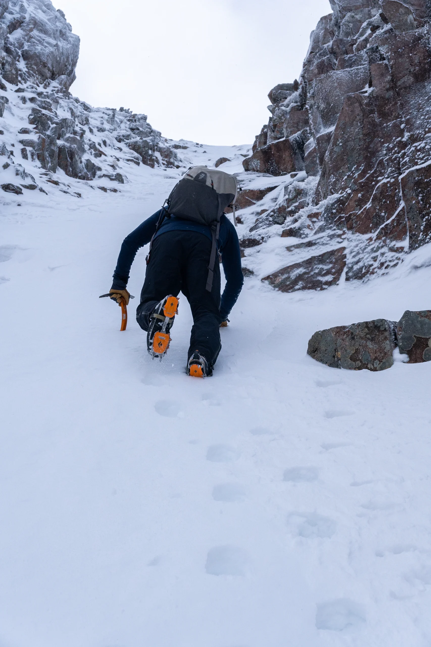 Klimmer die met stijgijzers een steile sneeuwhelling op loopt