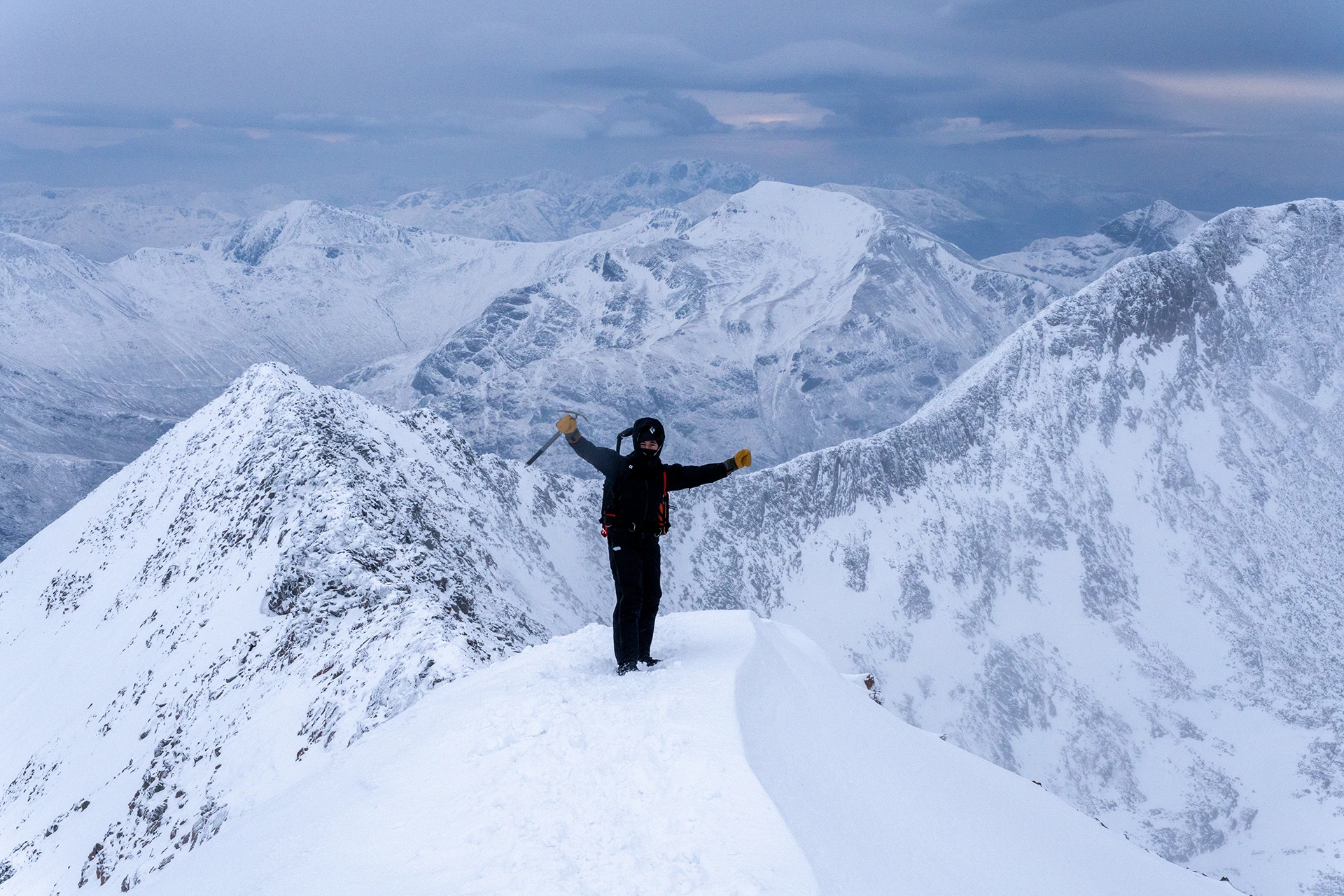 Persoon die alleen op een smalle sneeuwkam staat tussen diepe dalen
