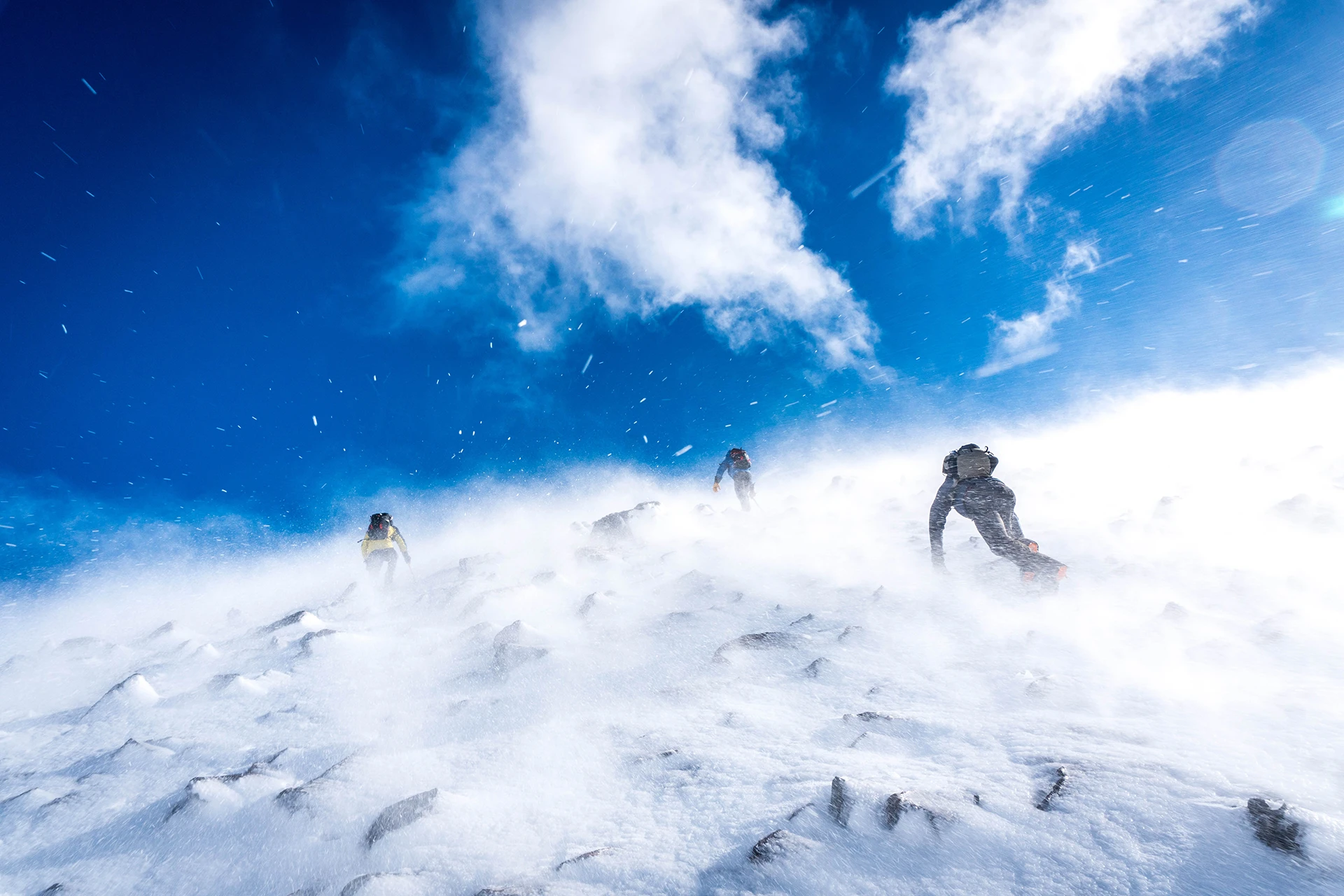 Klimmer die door een sneeuwstorm over een bergtop gaat