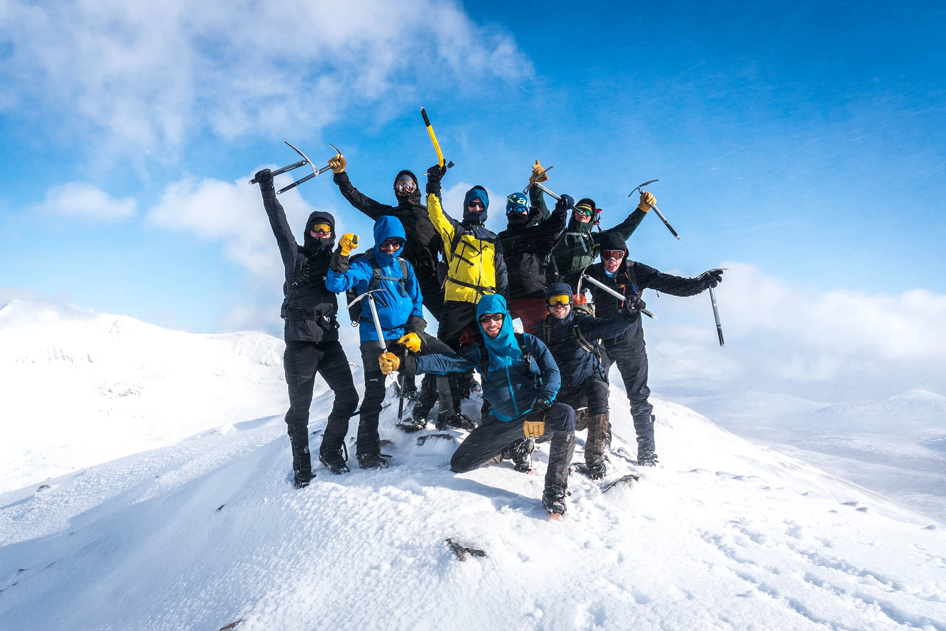Groep klimmers die op een besneeuwde top juicht