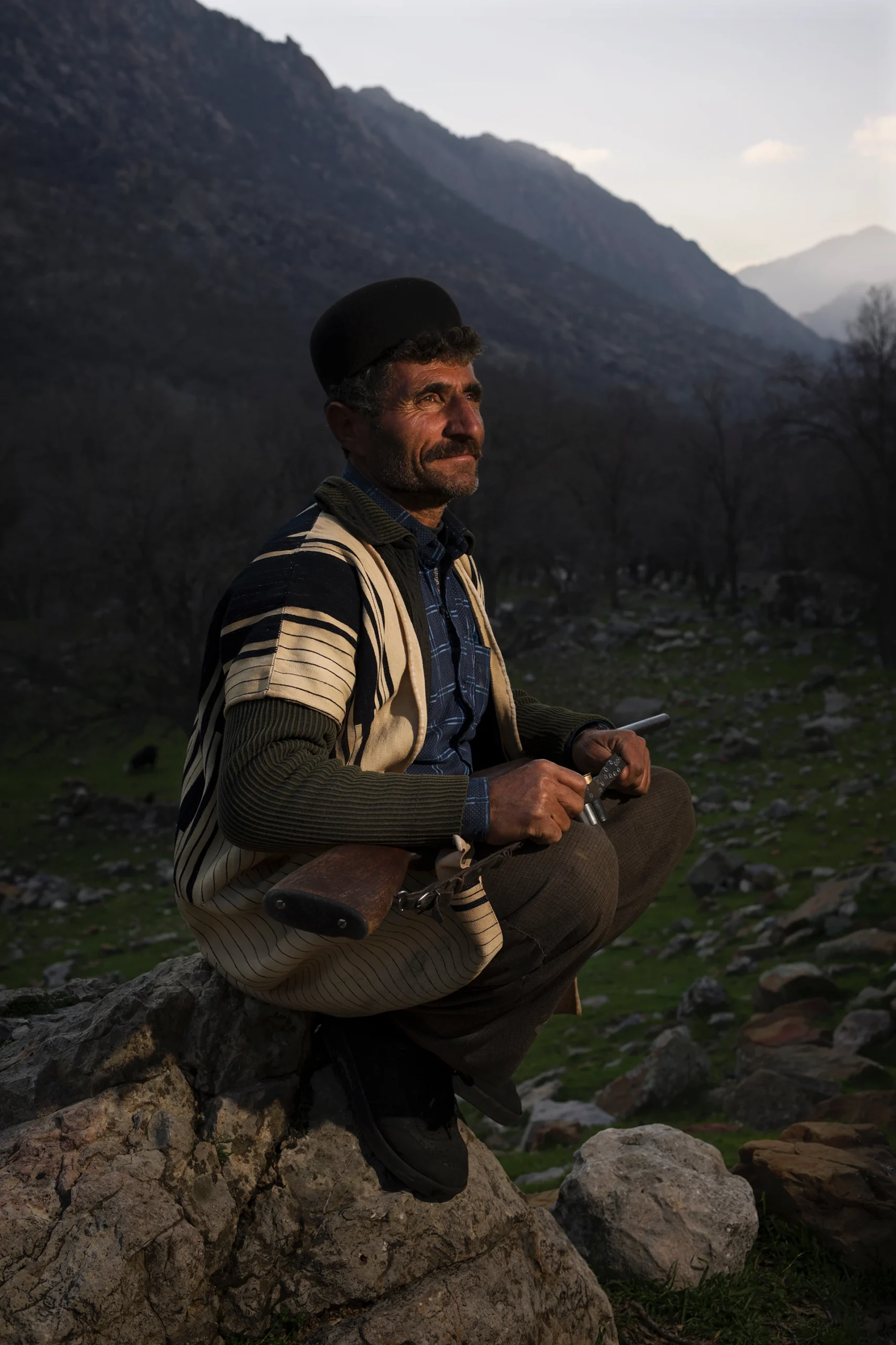 Man die in avondlicht zit met uitrusting op zijn schoot