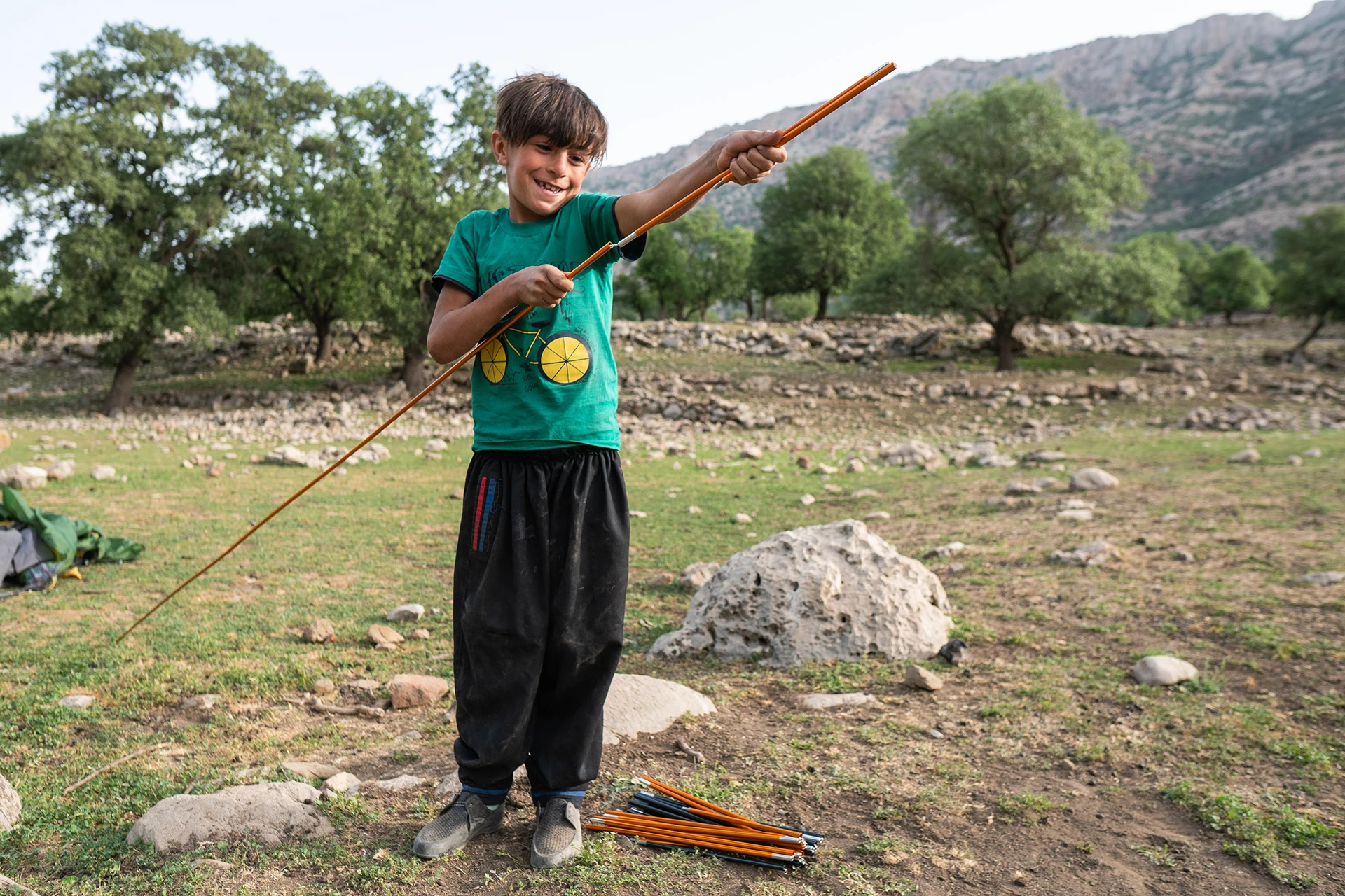 Jongen die met een stok in een open veld speelt