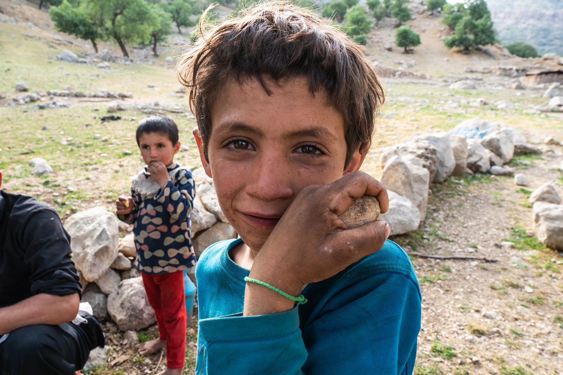 Rijtje tenten op een open grasvlakte met bomen erachter