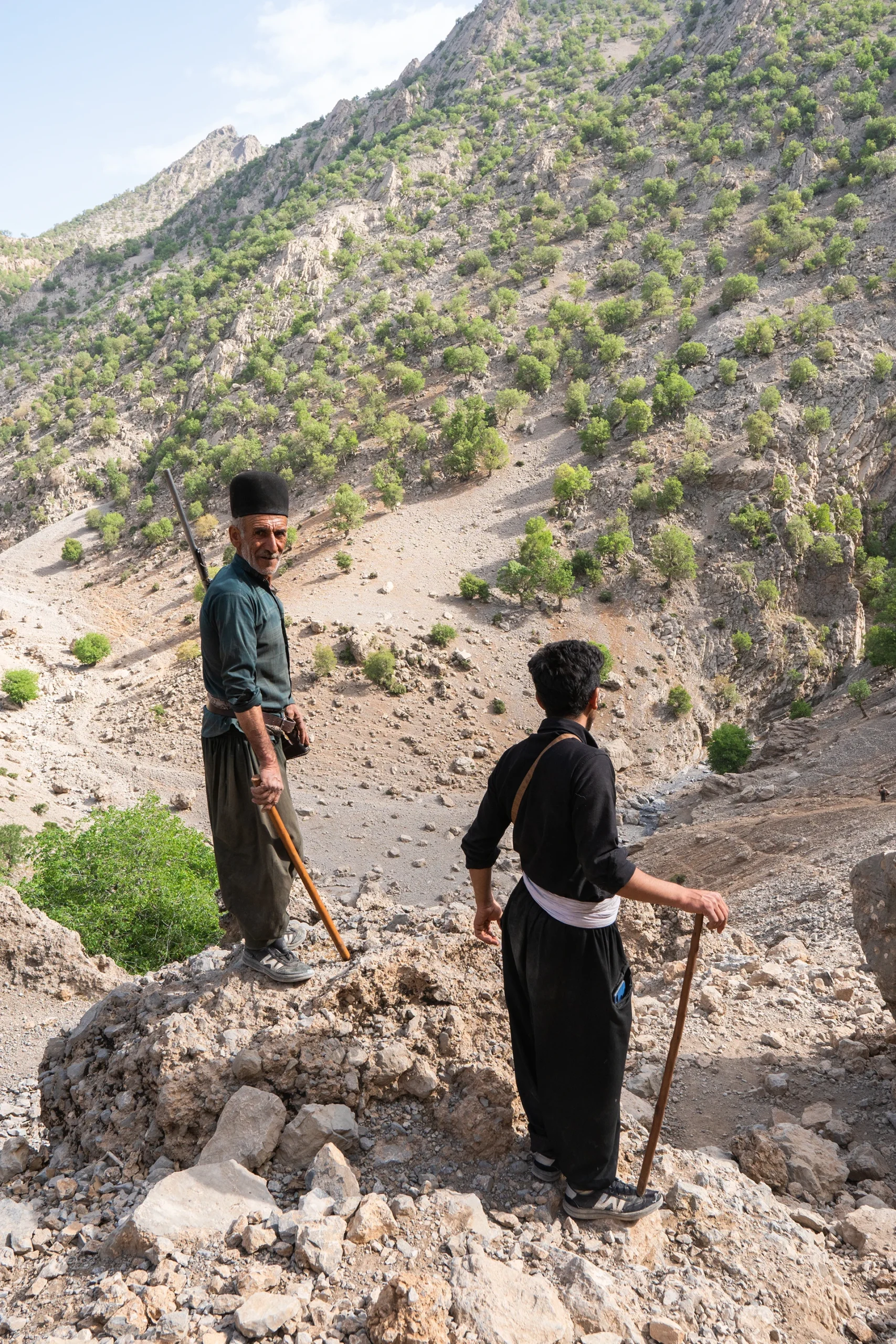 Hiker die door een groene vallei loopt langs een rotswand