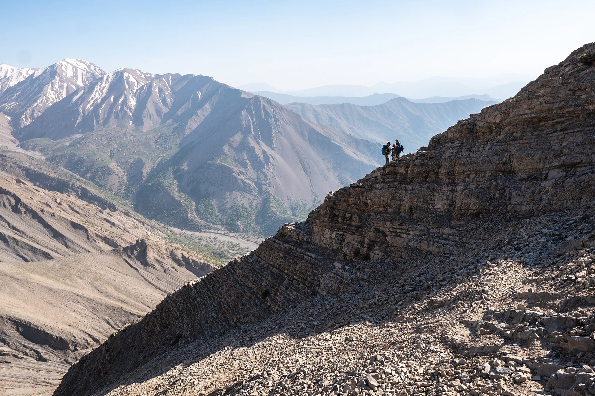 Wandelaar die over een rotsgraat loopt met diepe valleien naast zich