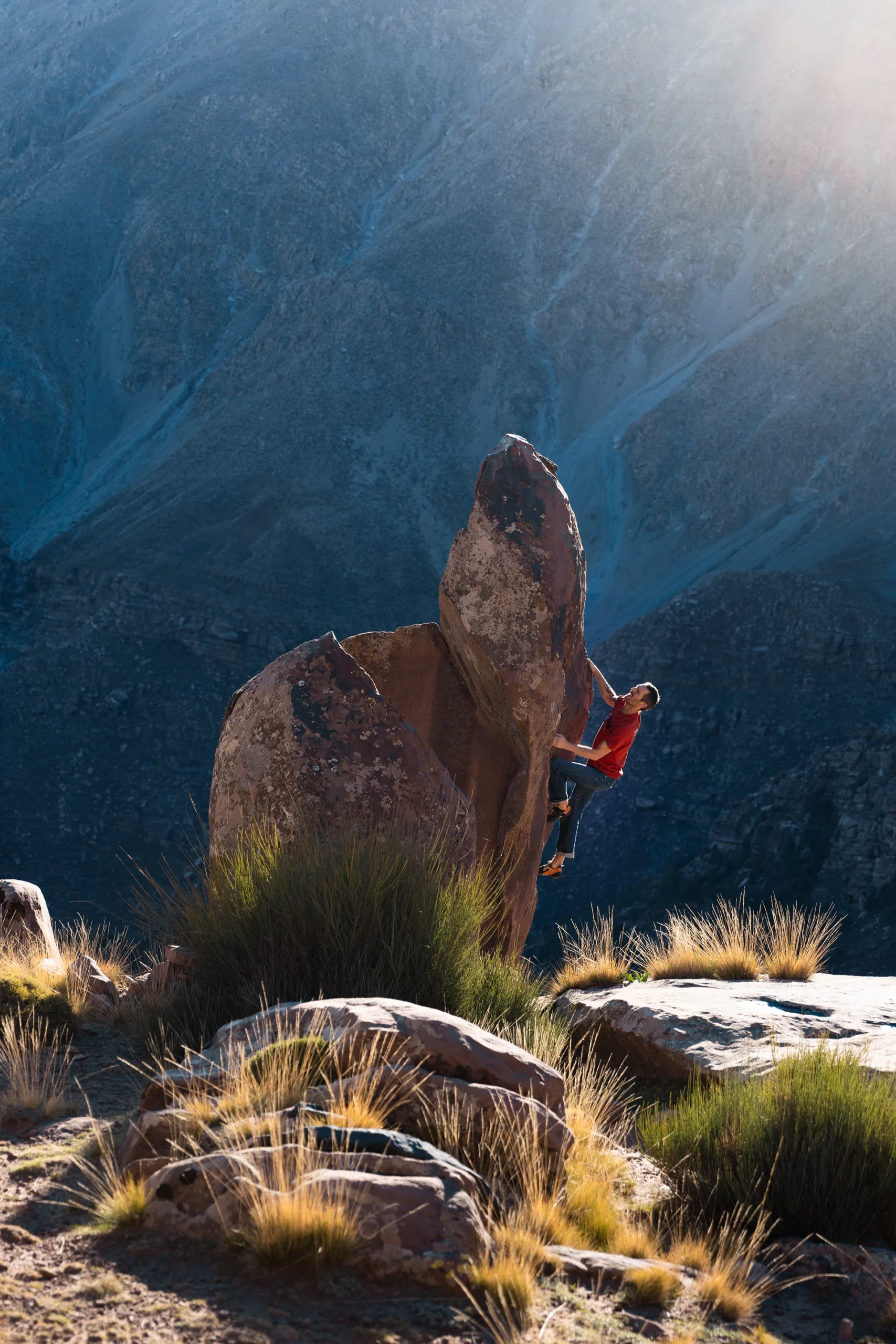 Klimmer die een boulder beklimt met zonlicht op de achtergrond