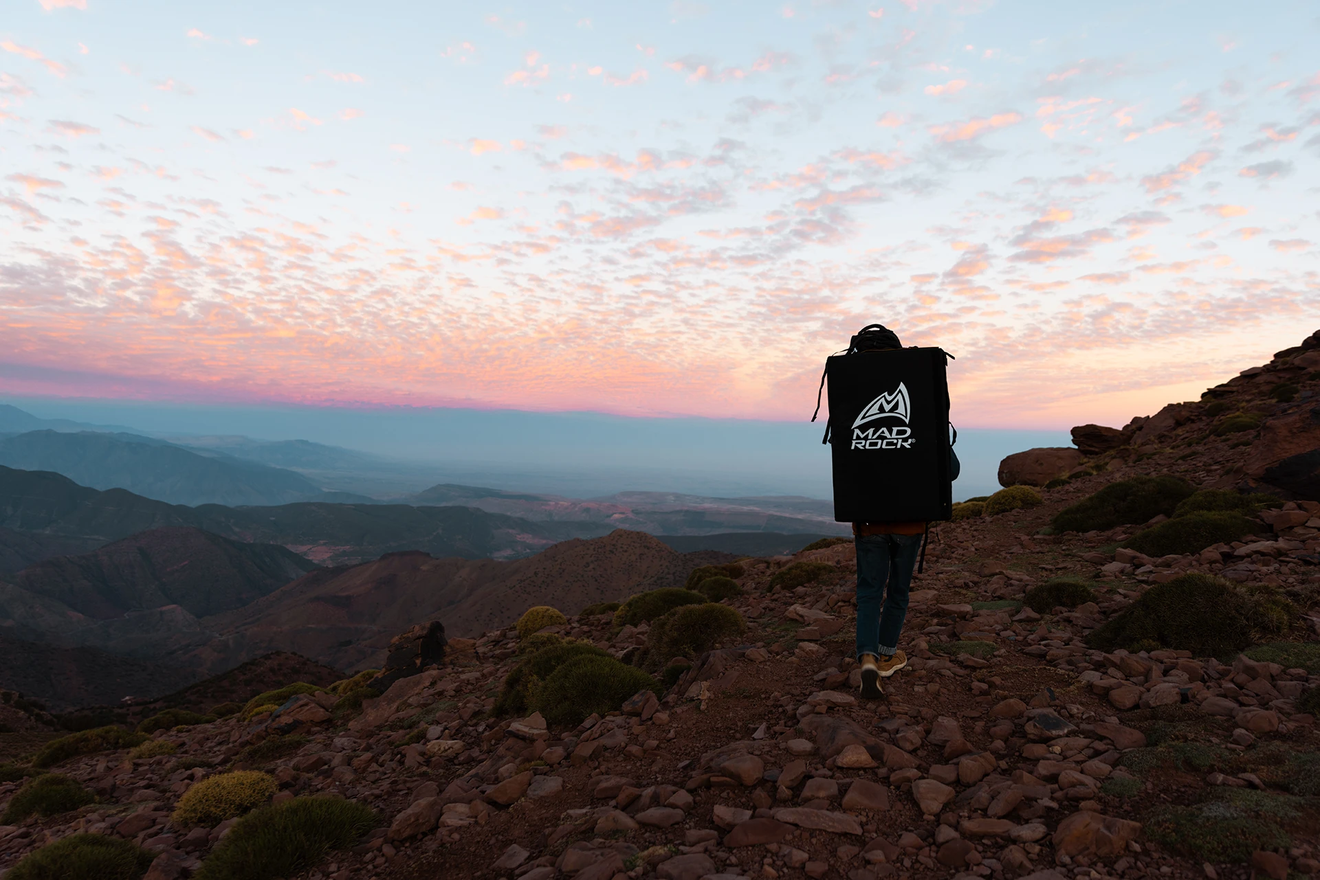 Klimmer die tegen een rotswand hangt in een droog berggebied