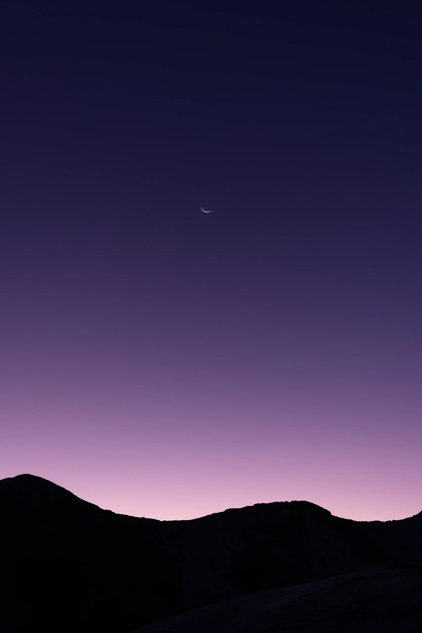 Paarse lucht boven bergsilhouetten bij avondschemer