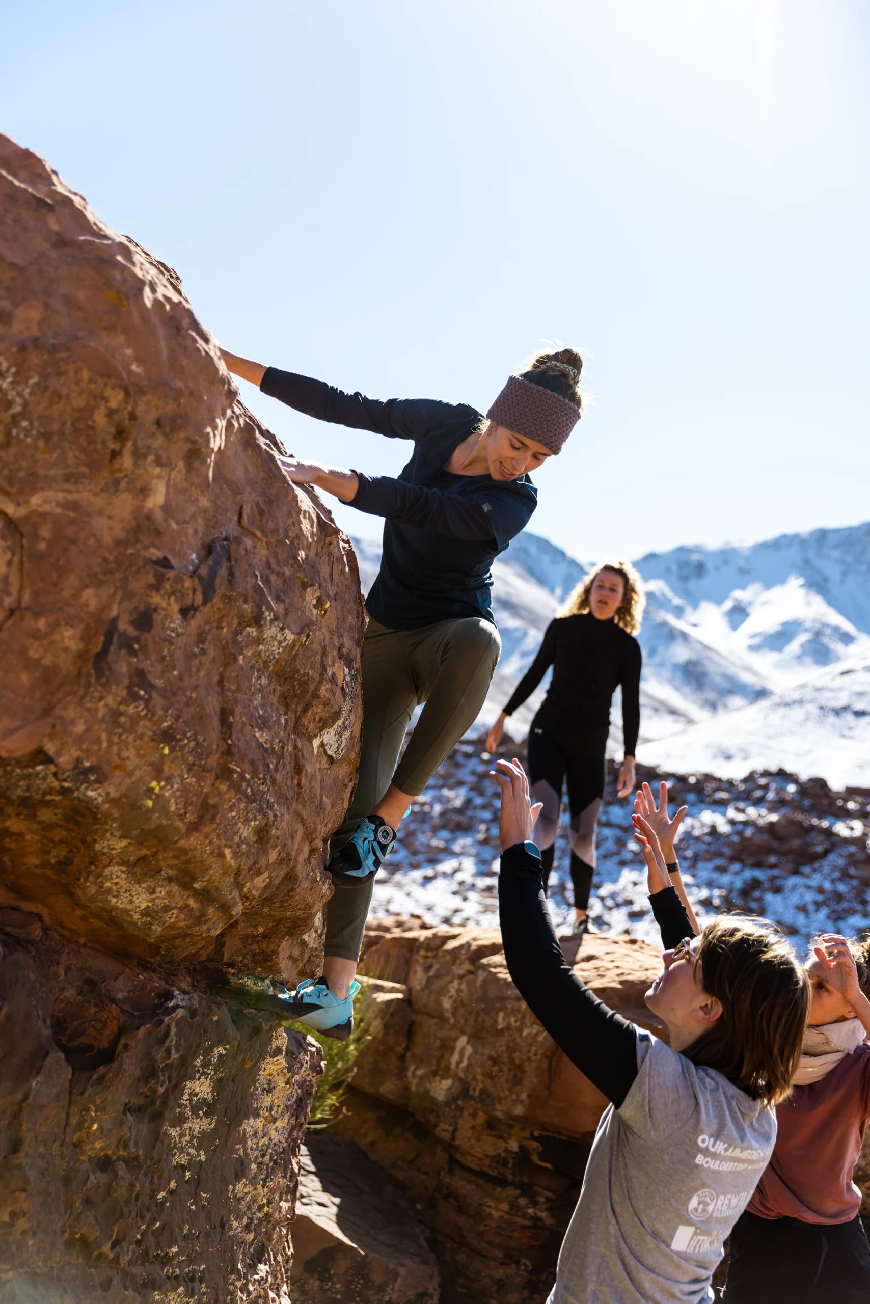 Klimmer die een boulder beklimt met een spotter ernaast