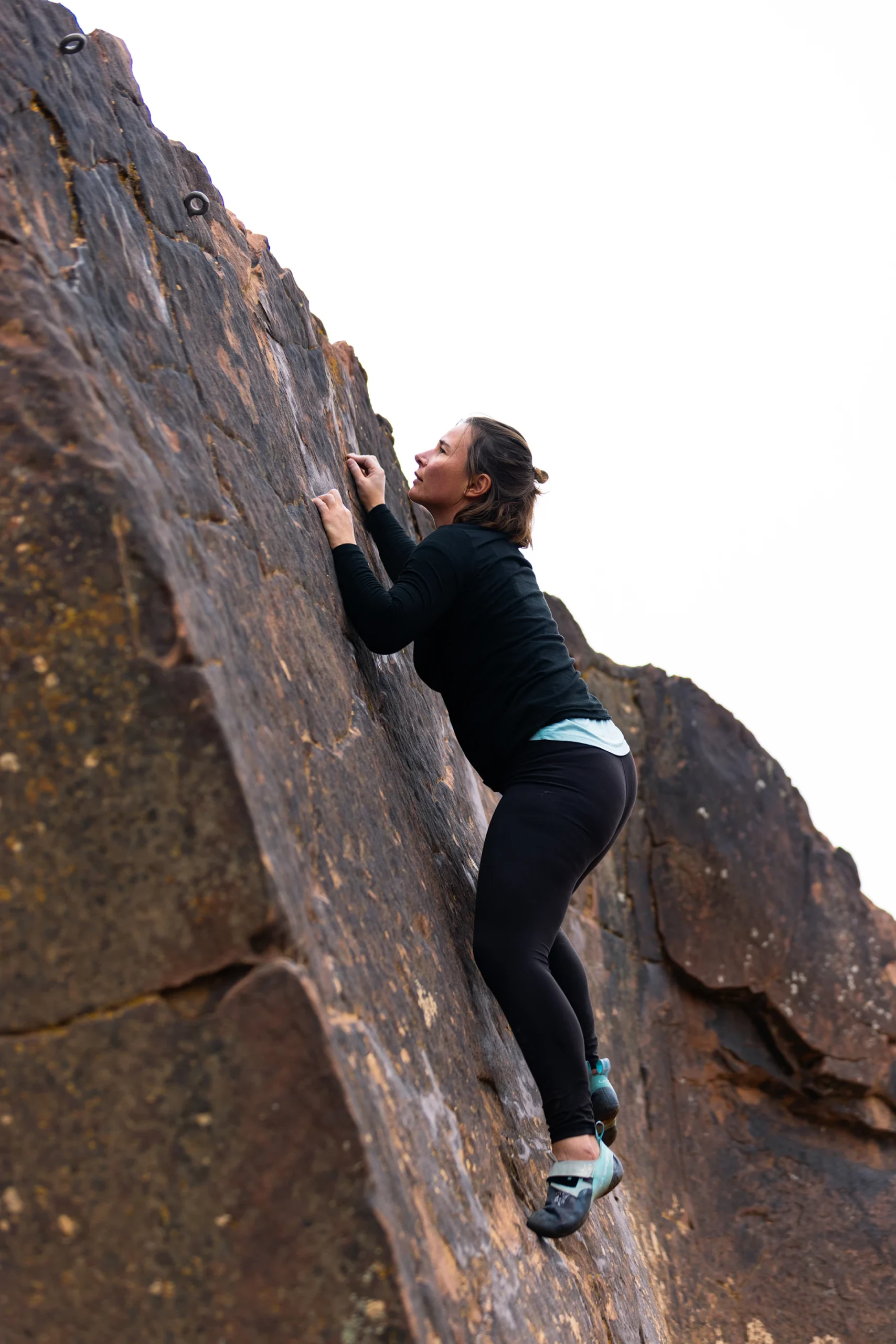 Klimmer die tegen een steile rotswand omhoog gaat