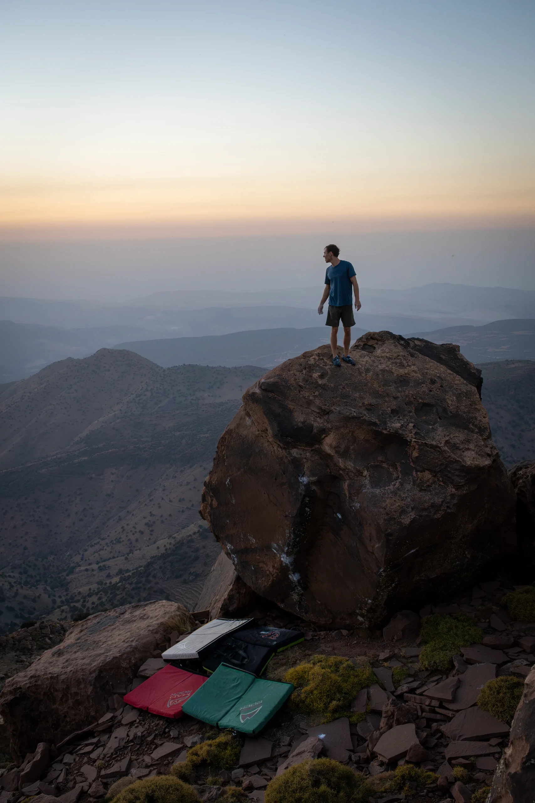 Persoon die op een rots staat bij zonsondergang met uitzicht over dalen