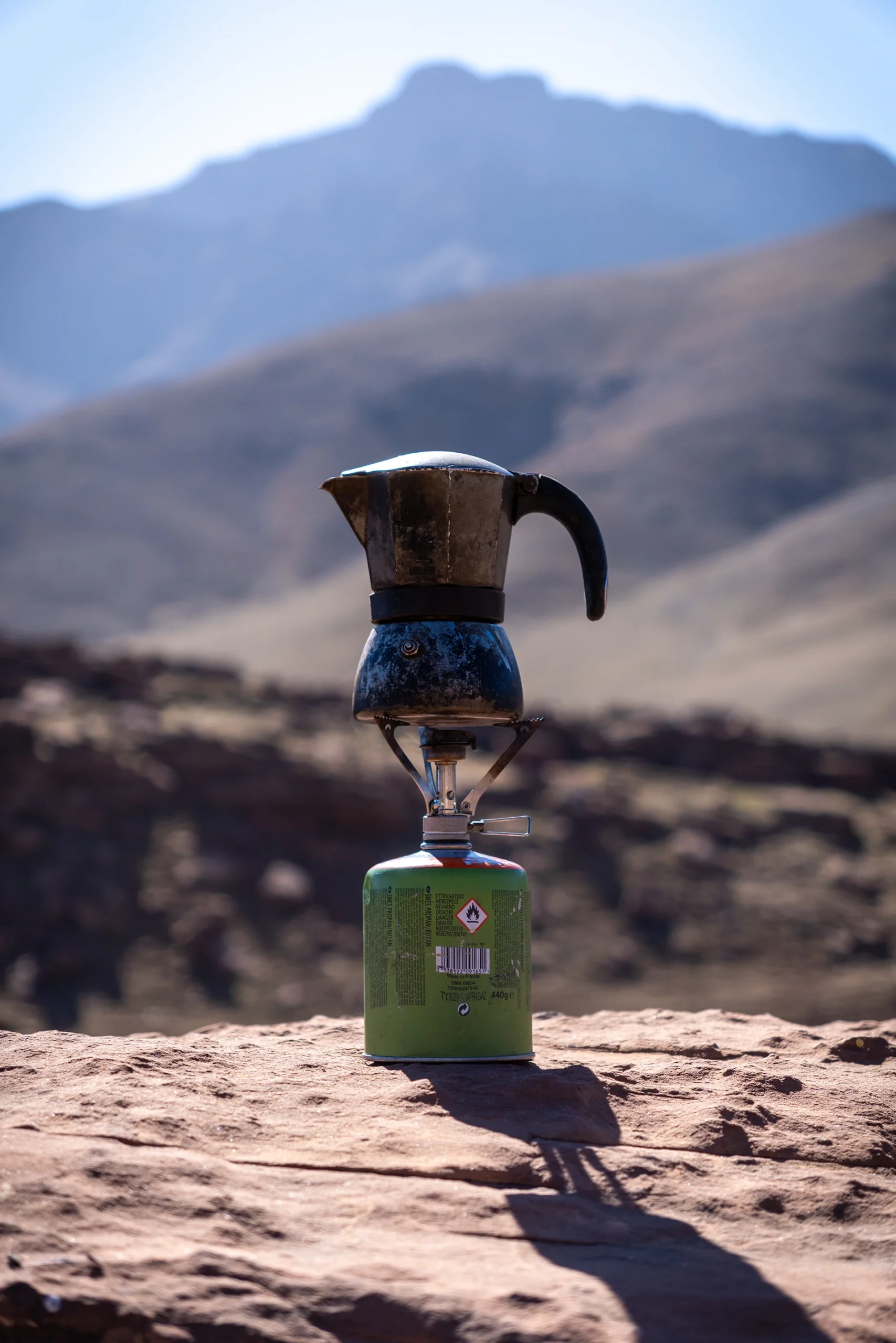 Koffiekan op een brander in een bergachtig landschap