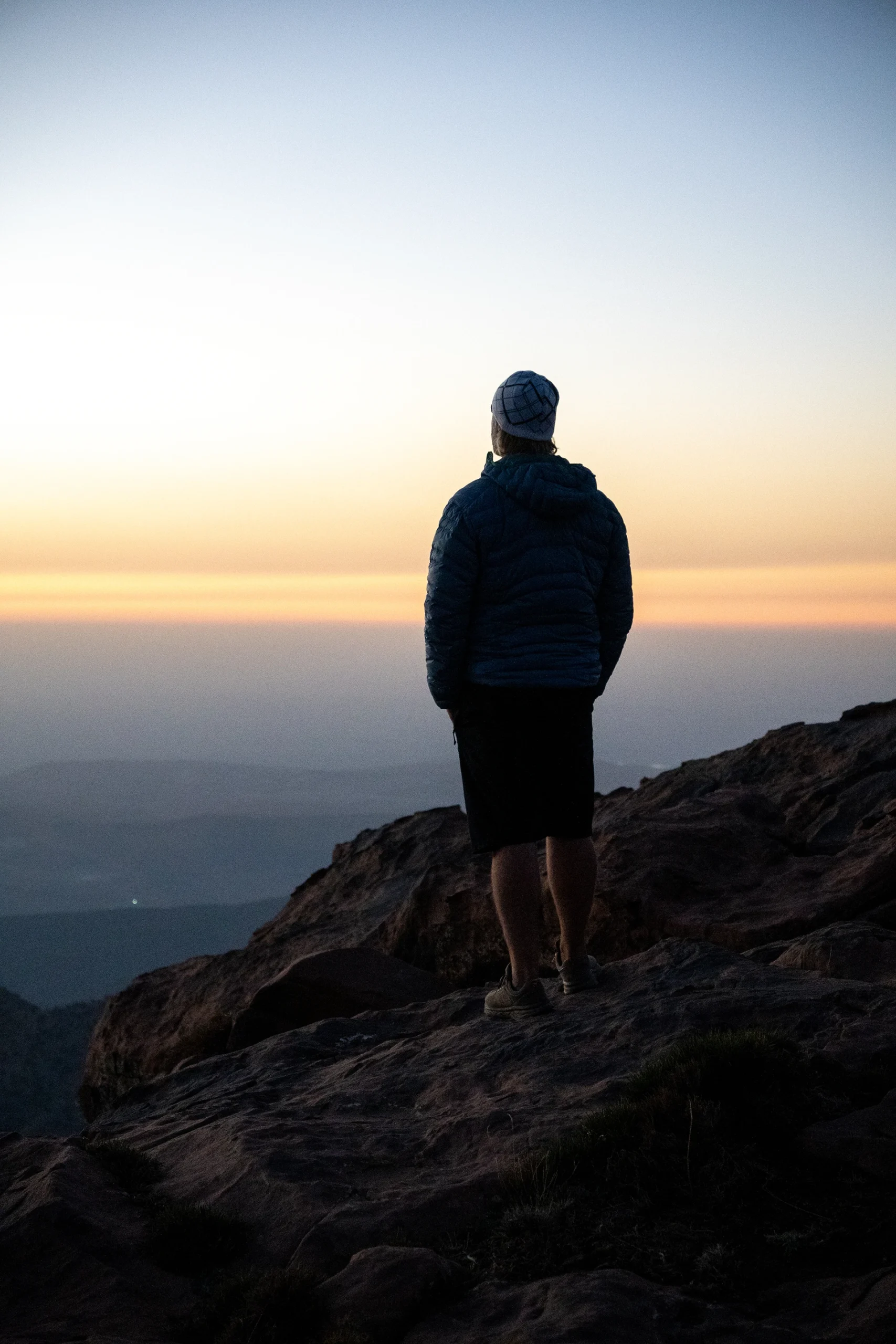 Persoon die bij zonsondergang op een rots staat