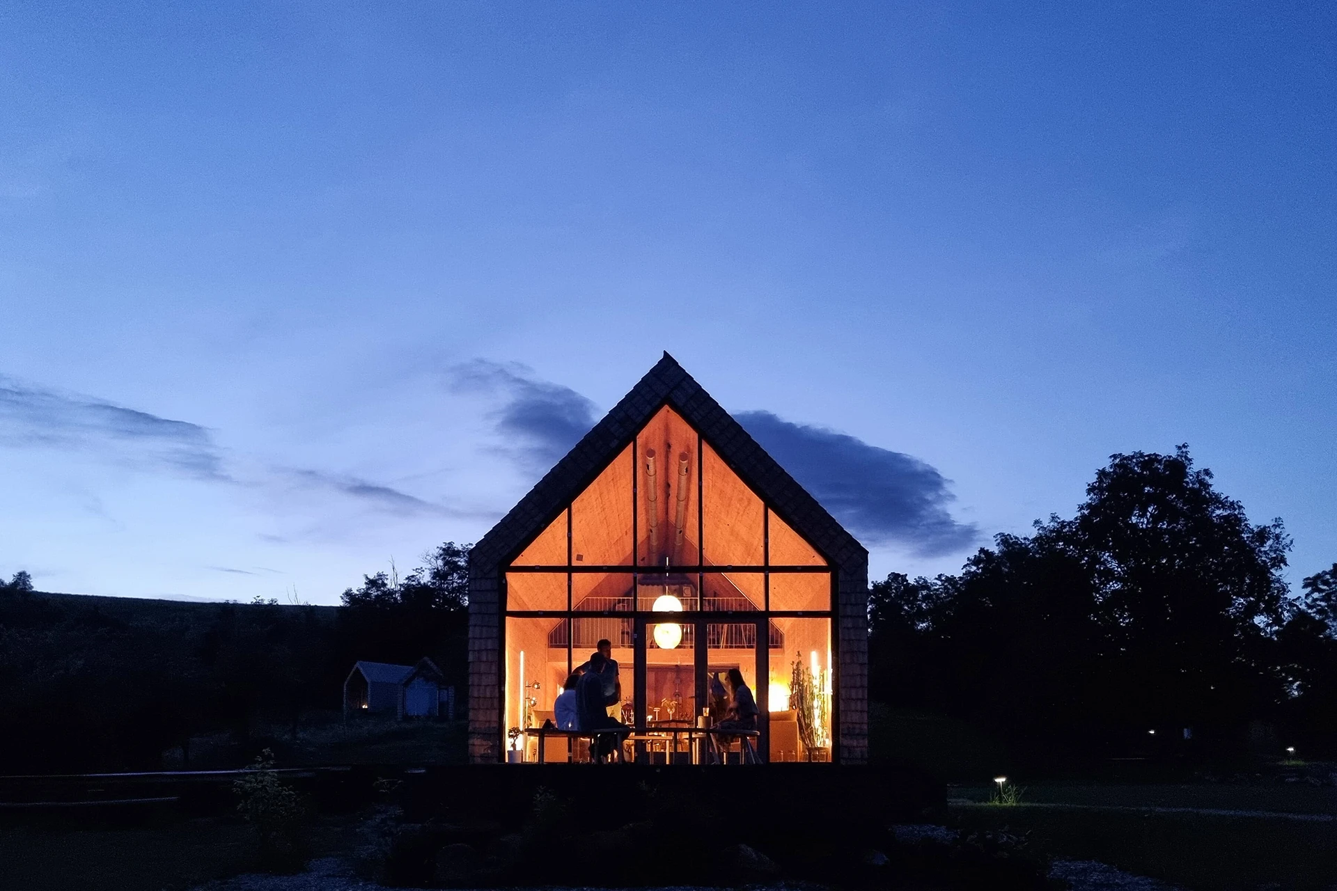 Modern huisje met glazen gevel in avondlicht