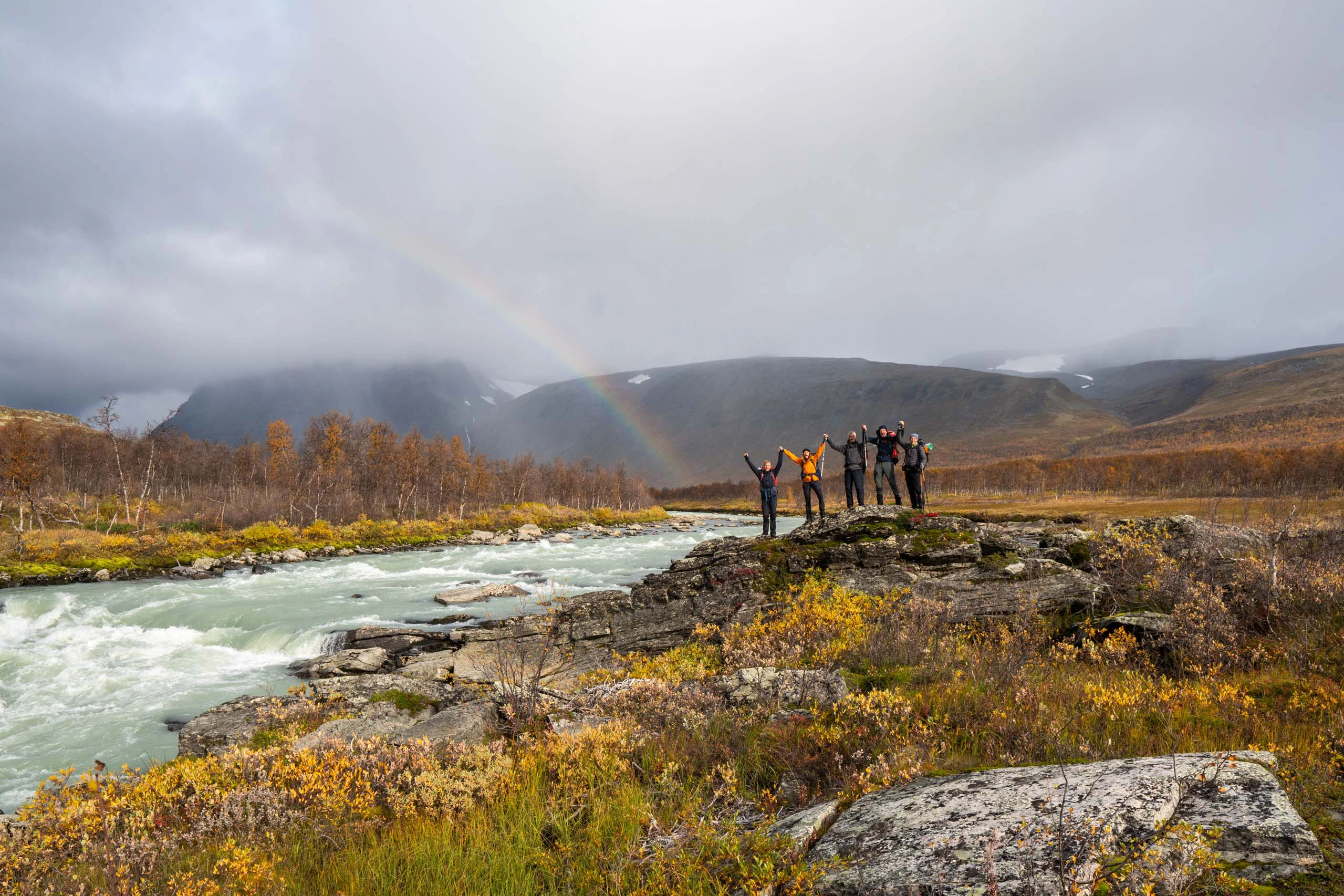 Wandelgroep die langs een rivier in herfstlicht loopt