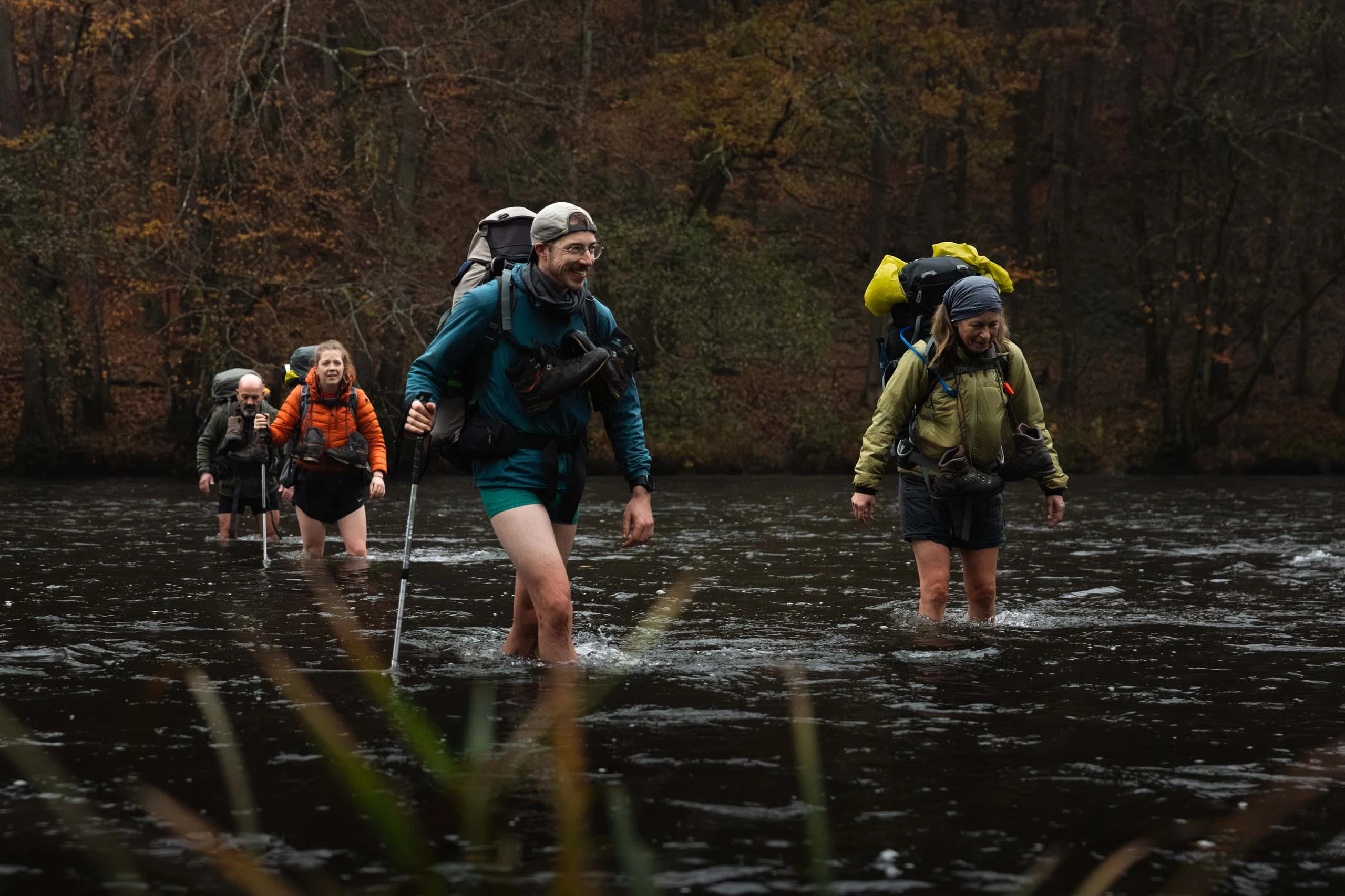 Wandelaars die een beek oversteken in dicht bos