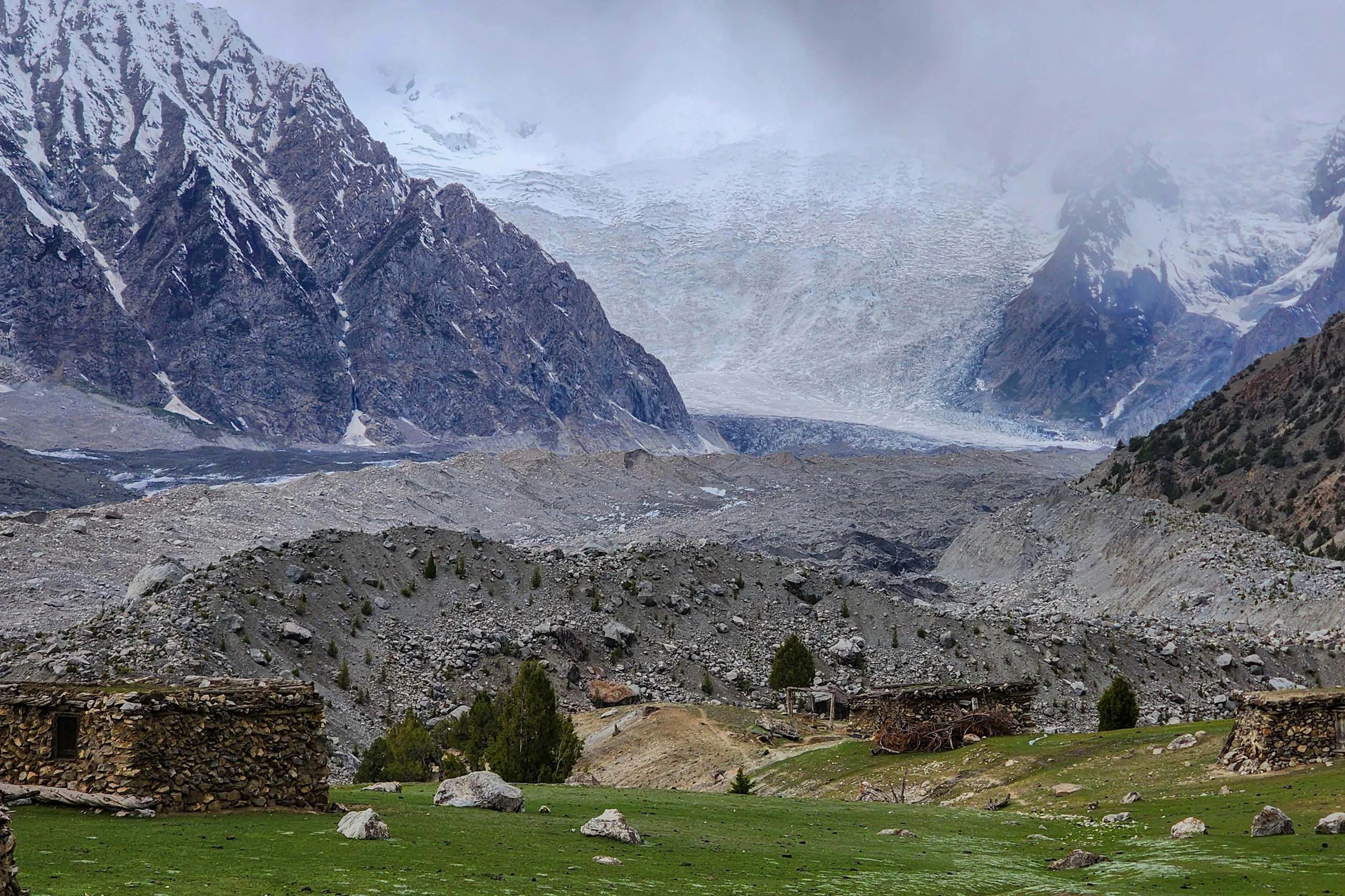Stenen ruïnes in een bergvallei met gletsjer en steile bergen