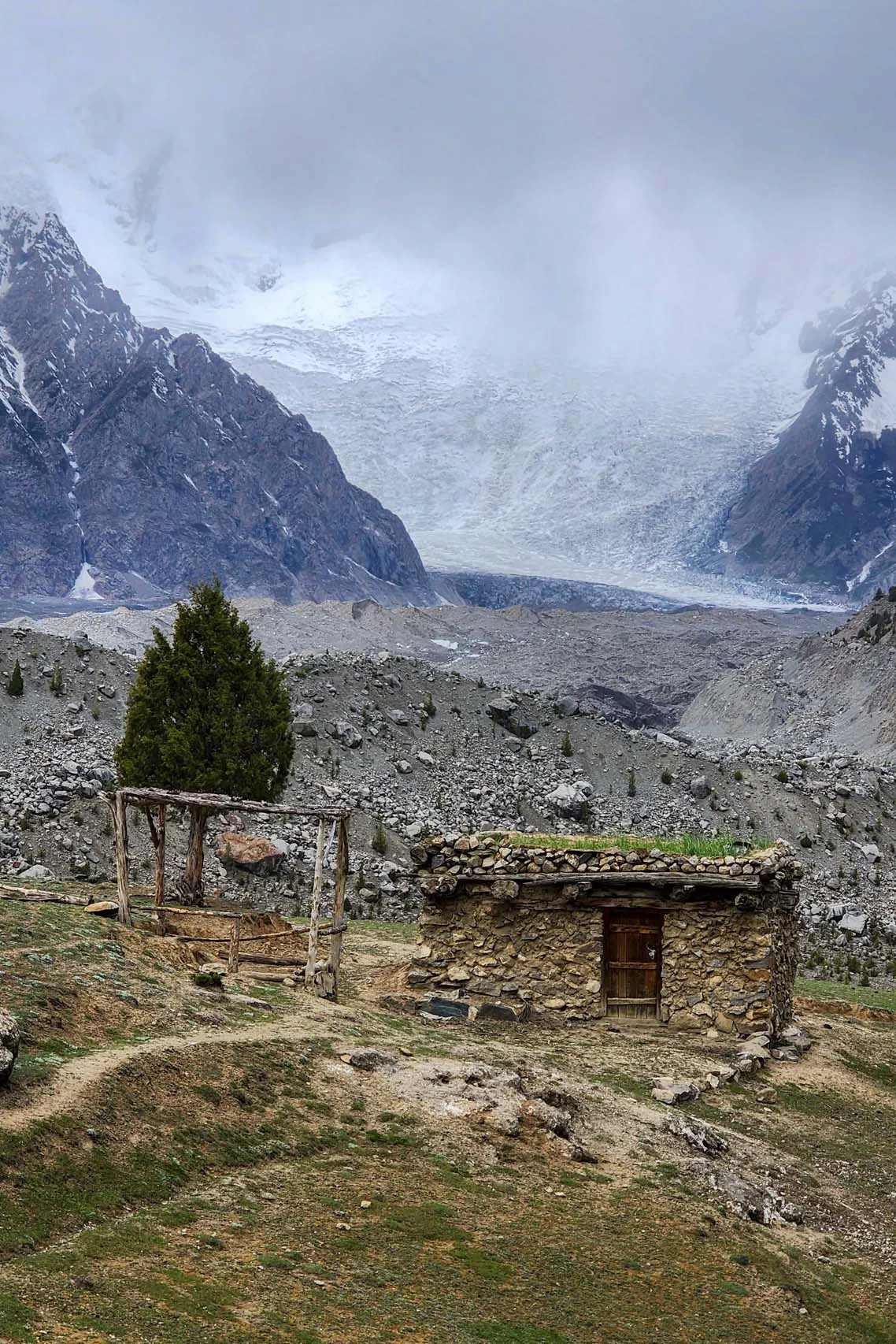 Kleine stenen hut in een bergvallei met gletsjer op de achtergrond
