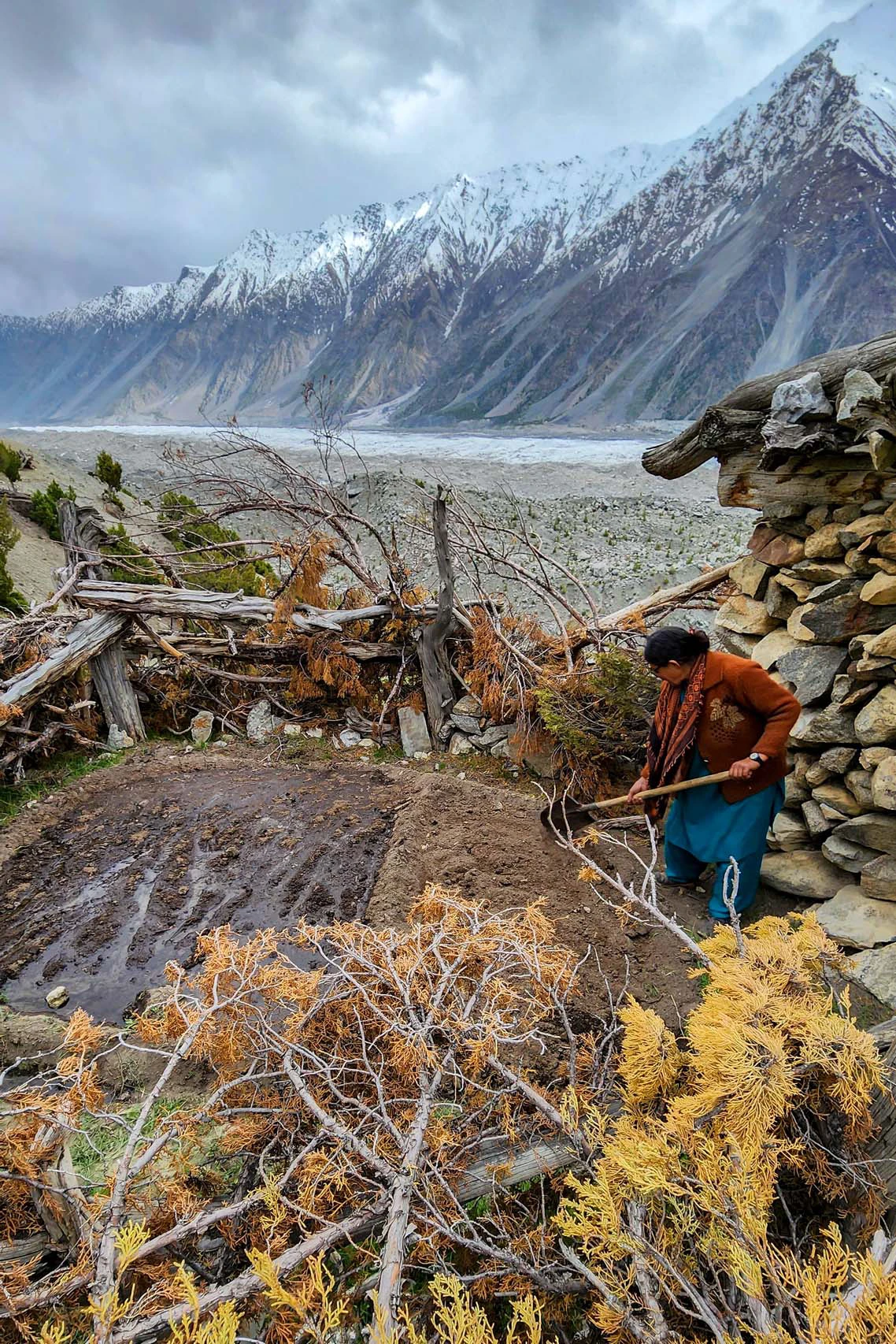Persoon werkt tussen stenen muren met uitzicht op een gletsjer en bergen