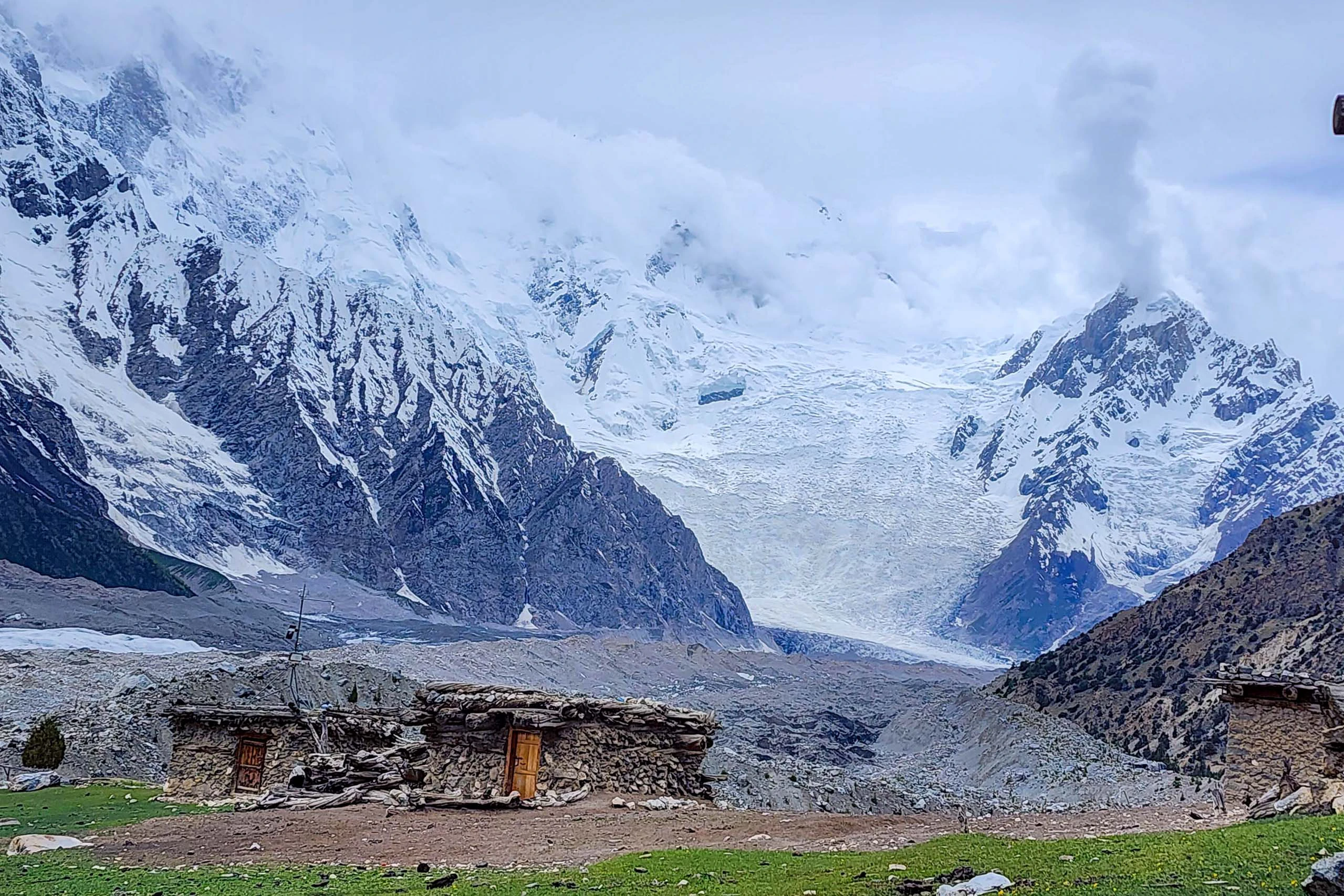 Sneeuwbedekte bergen en gletsjer met kleine hutten in het dal