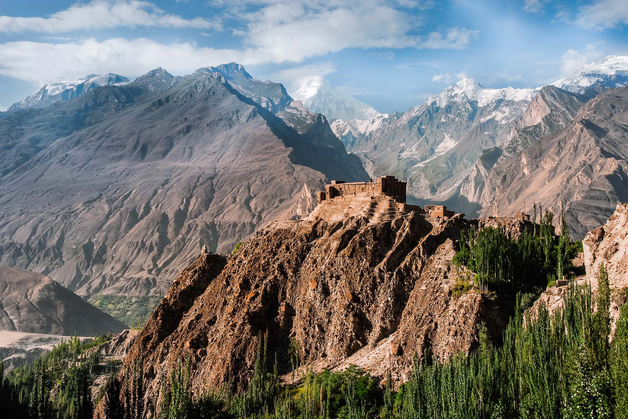 Rotsachtige bergkam met groene hellingen en hoge pieken op de achtergrond