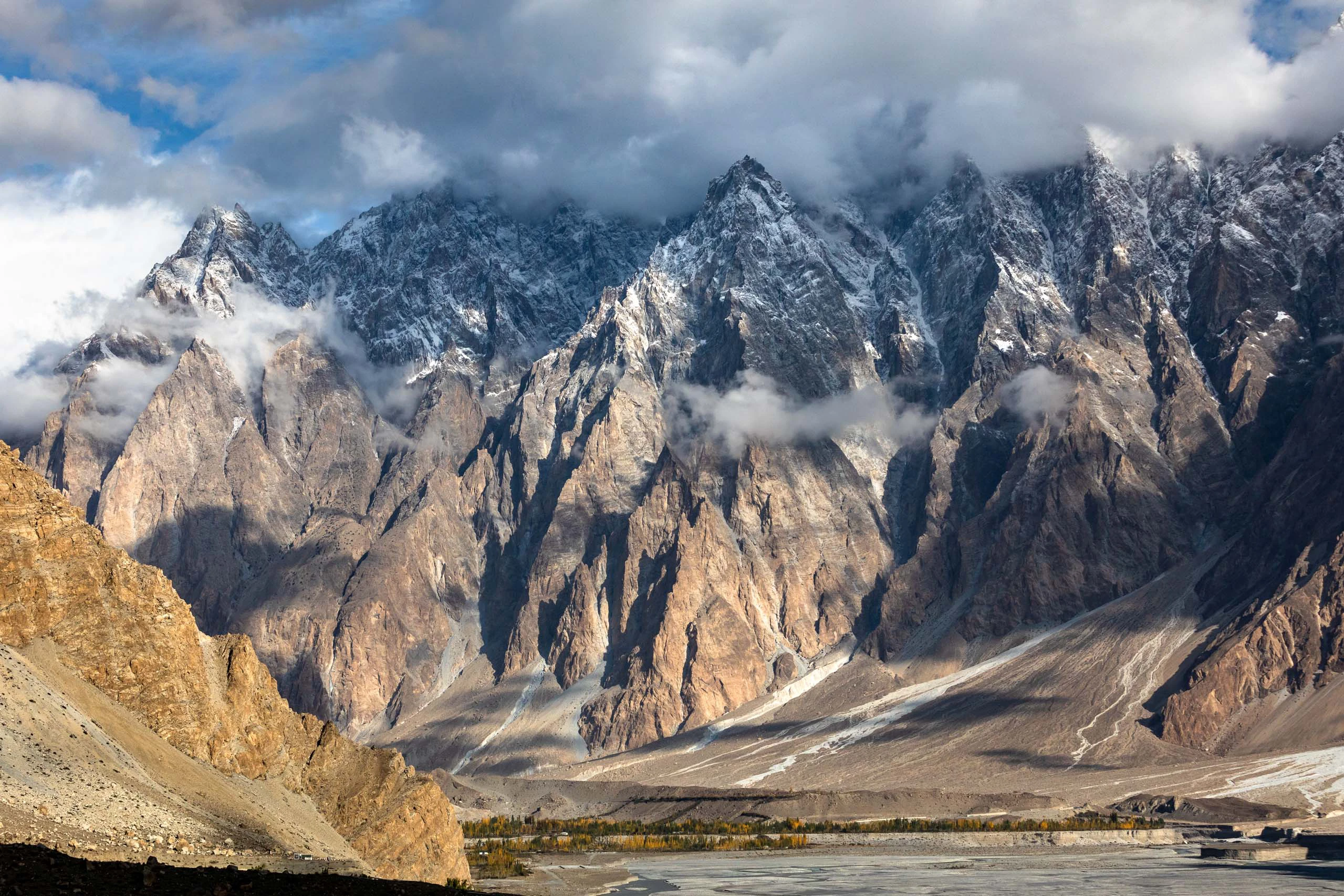 Steil rotsachtig bergmassief met sneeuwresten en donkere wolken