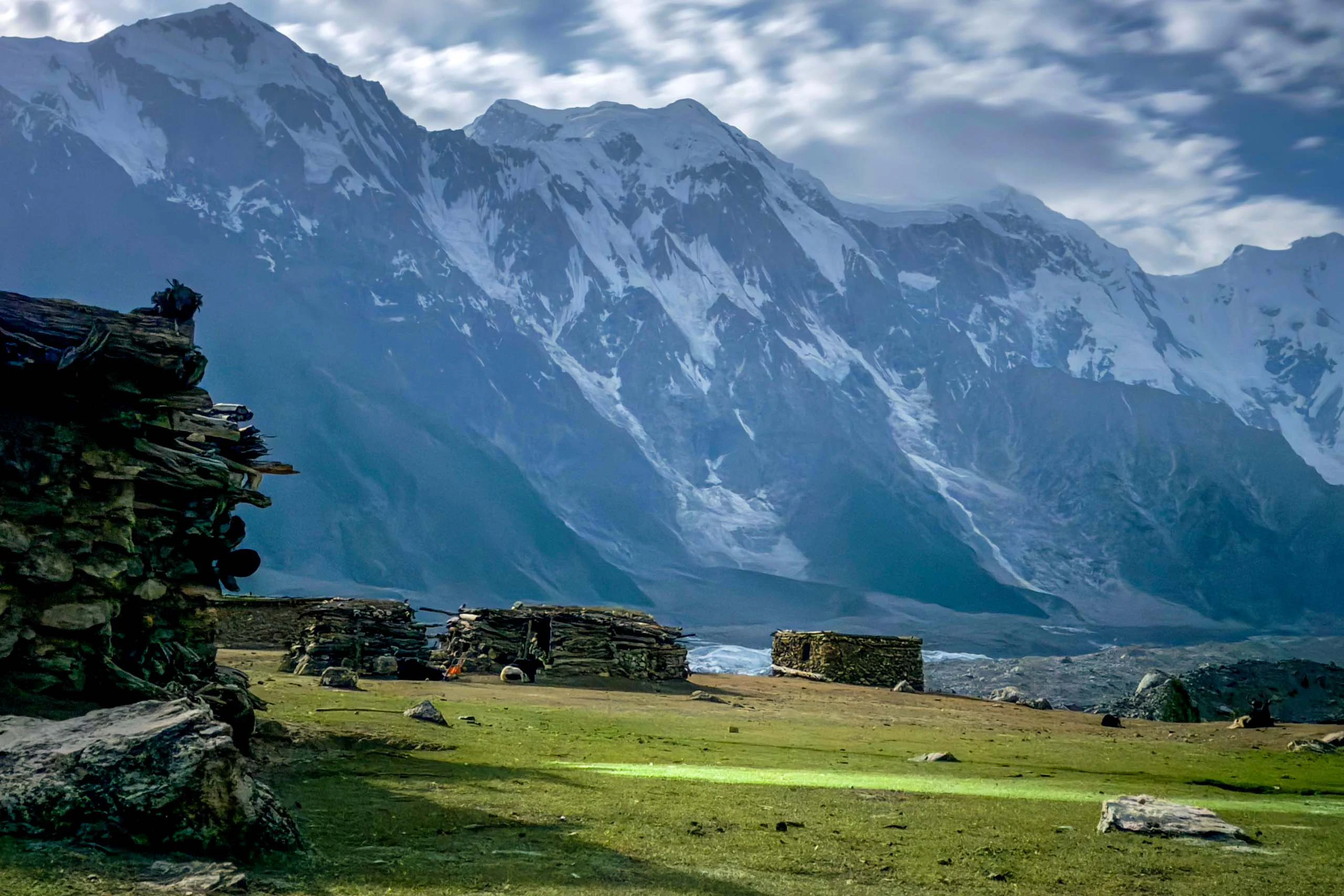 Groene vallei met houten huisjes en steile bergen op de achtergrond